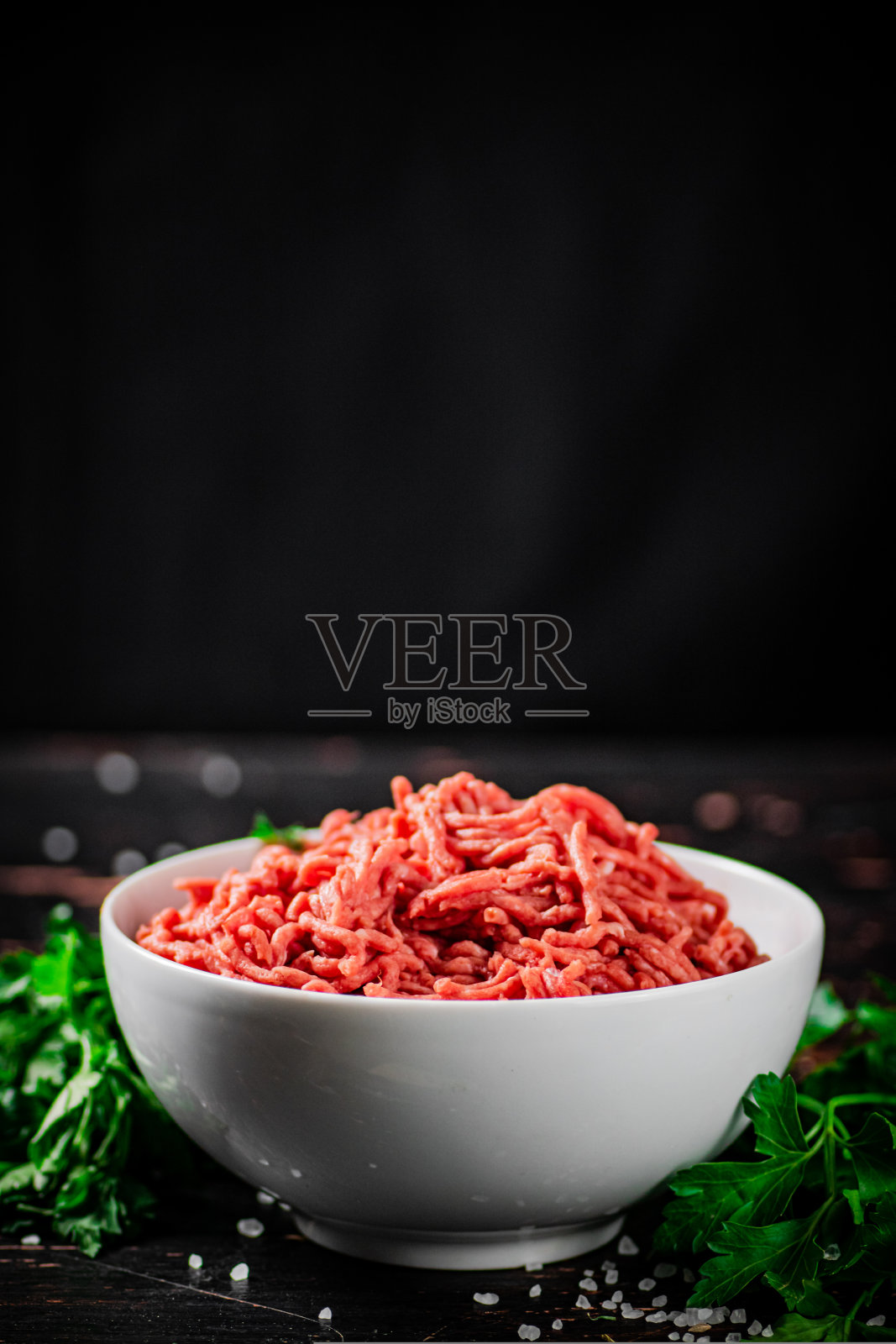 满满一碗肉末放在桌上，配上欧芹。照片摄影图片