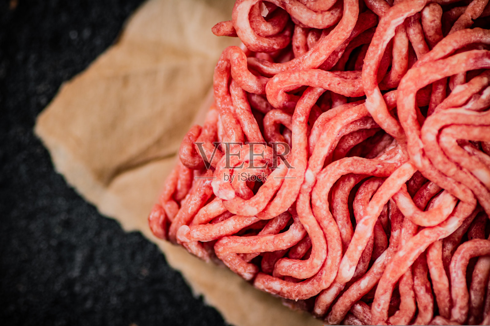 把生肉末放在纸上放在桌上。照片摄影图片