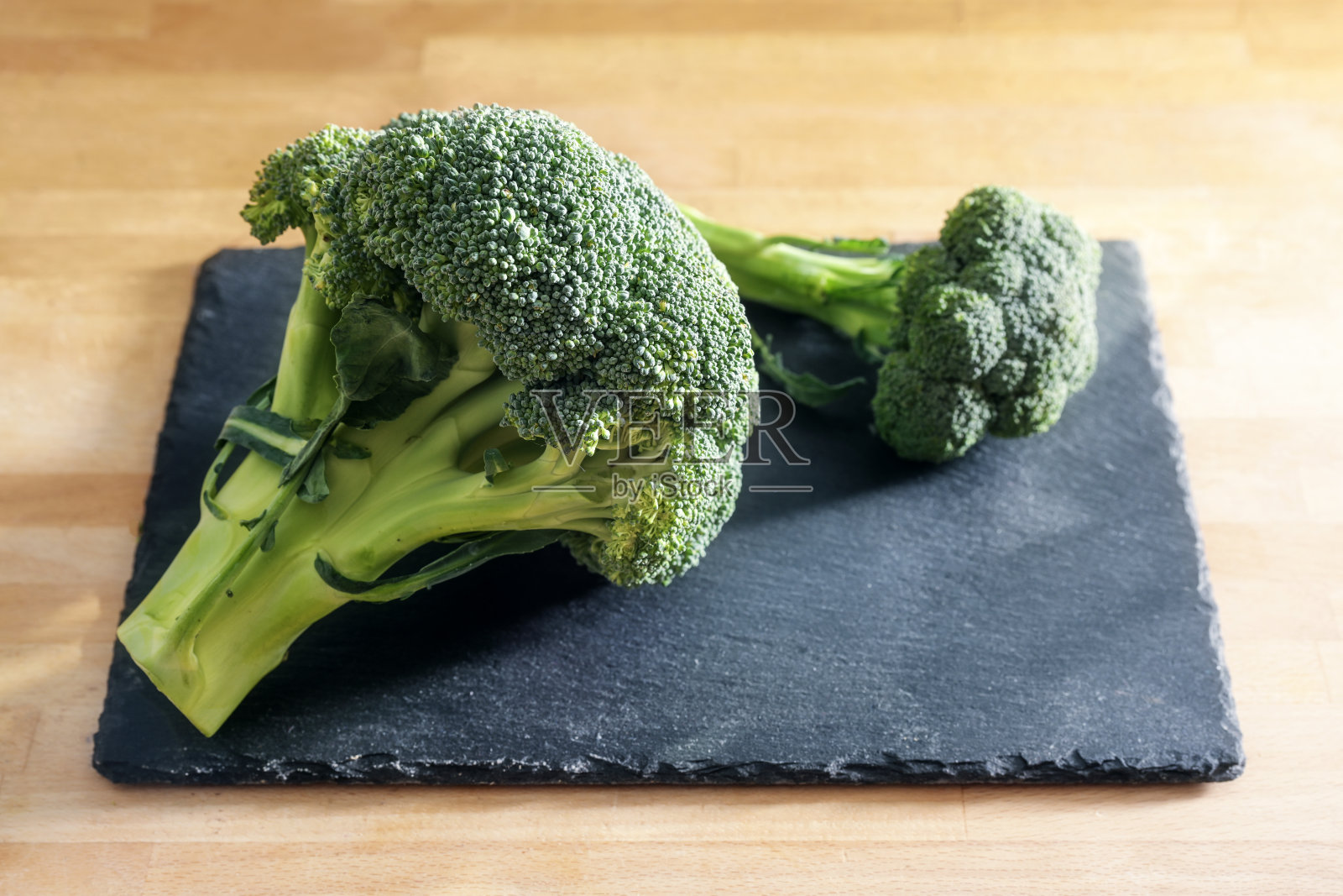 石板盘和木制厨房桌子上的生西兰花，烹饪蔬菜的准备，健康素食餐的配料，复制空间，选定的重点照片摄影图片