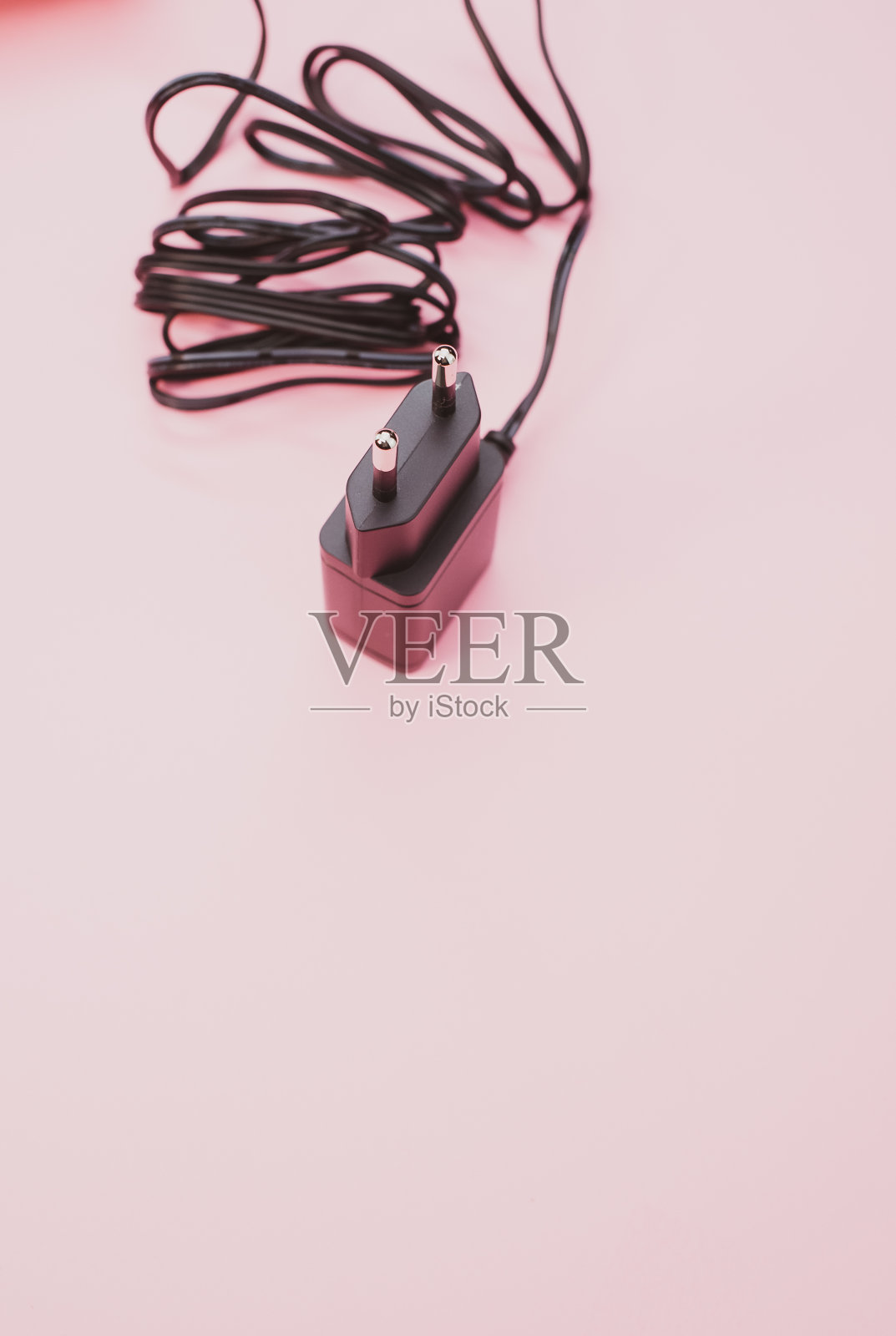 垂直拍摄的有线充电器适配器隔离在粉红色的背景照片摄影图片