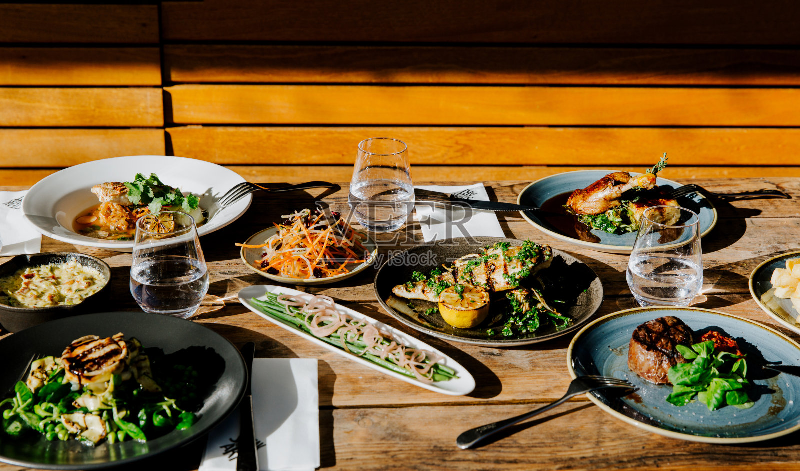 木制的户外桌子，上面放着不同的盘子照片摄影图片