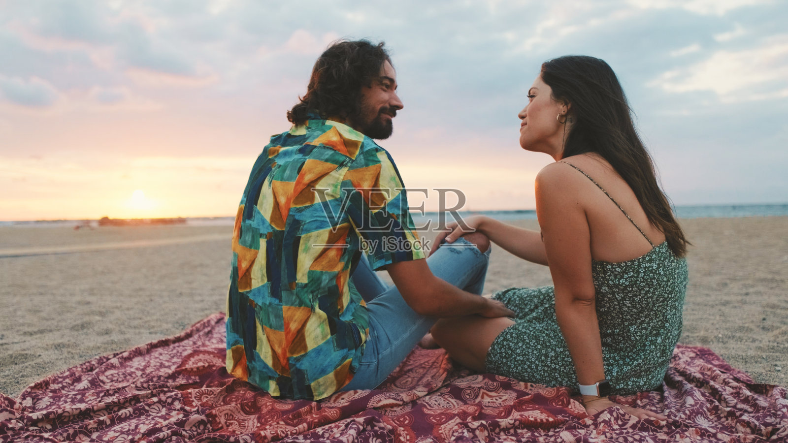 日出时分，一男一女在海滩上交谈照片摄影图片