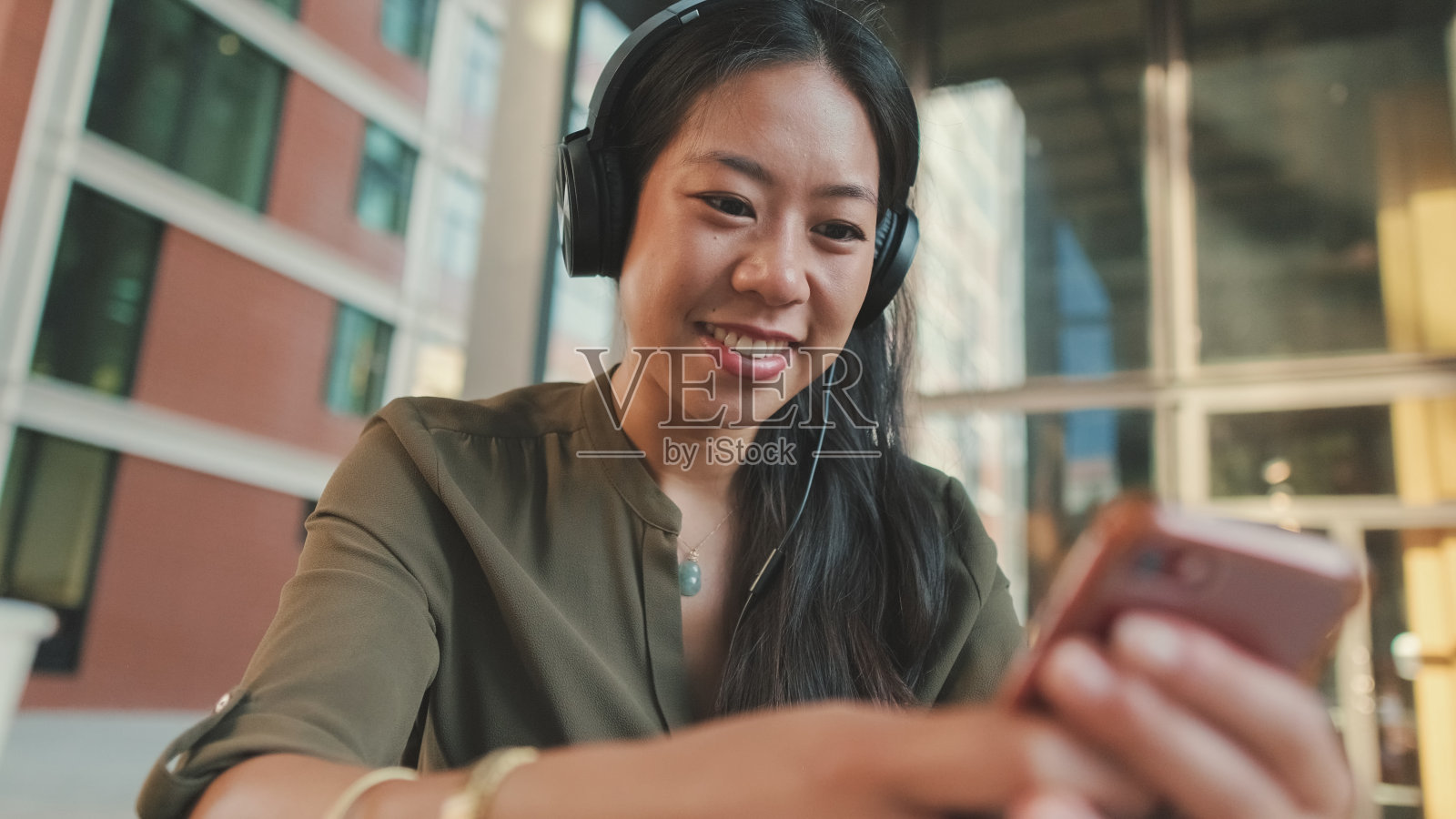 年轻的笑着戴着耳机的自由职业者使用手机工作照片摄影图片