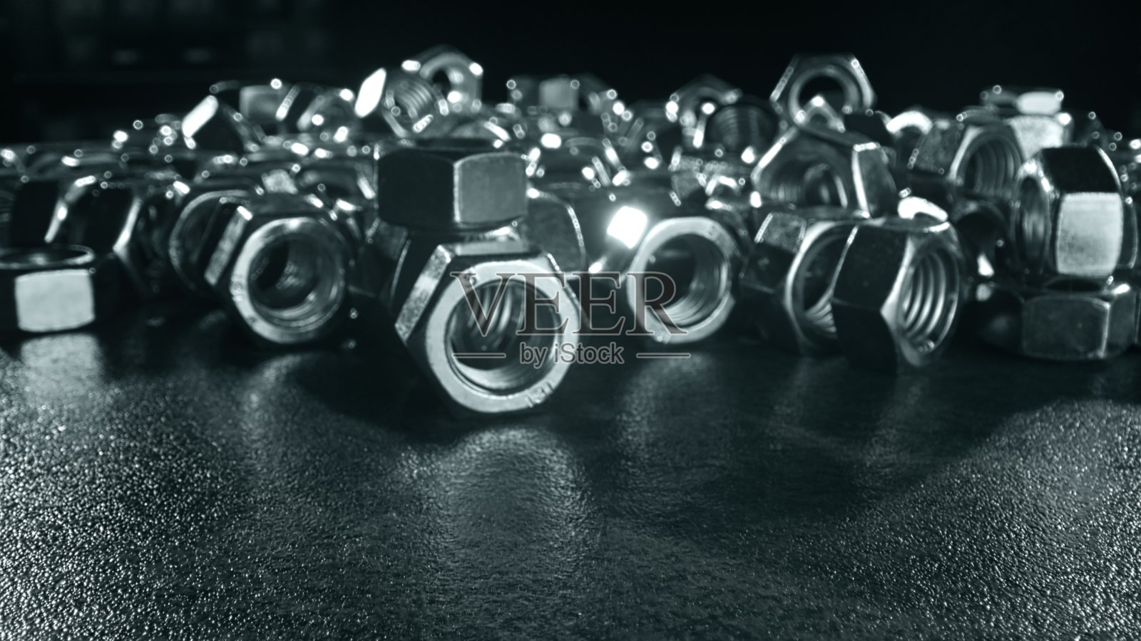 巨大的堆银螺母紧固件散落在黑色的桌子上照片摄影图片