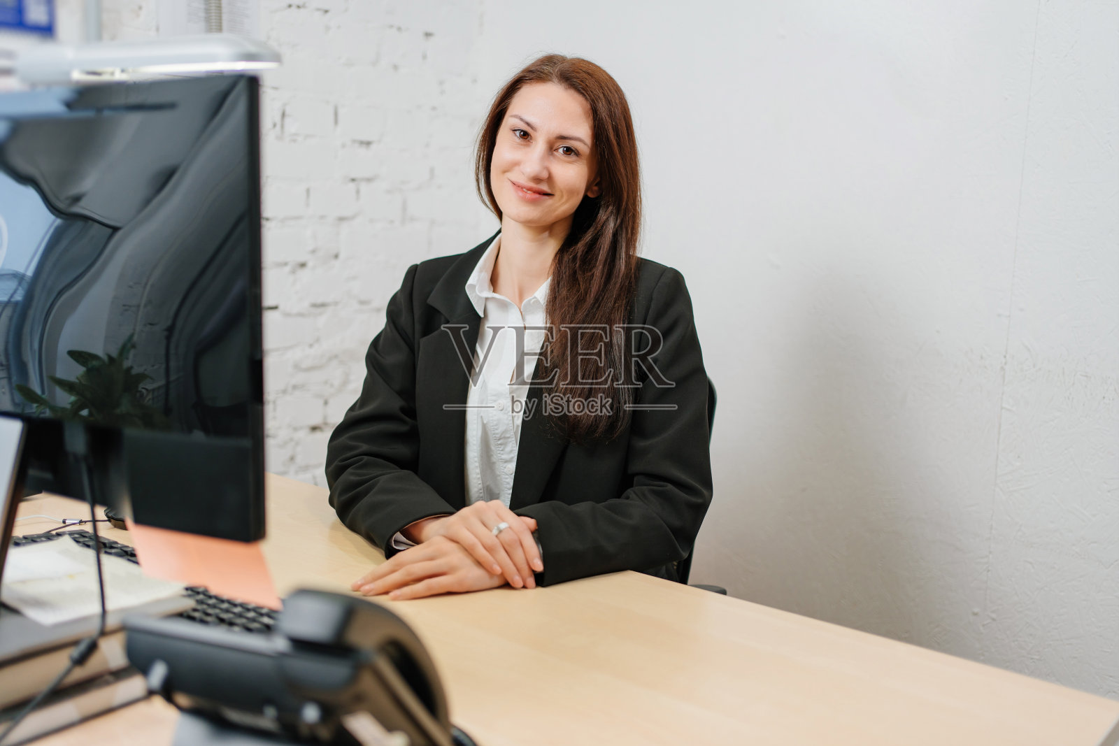 一个黑发女人在办公室的电脑前工作。照片摄影图片
