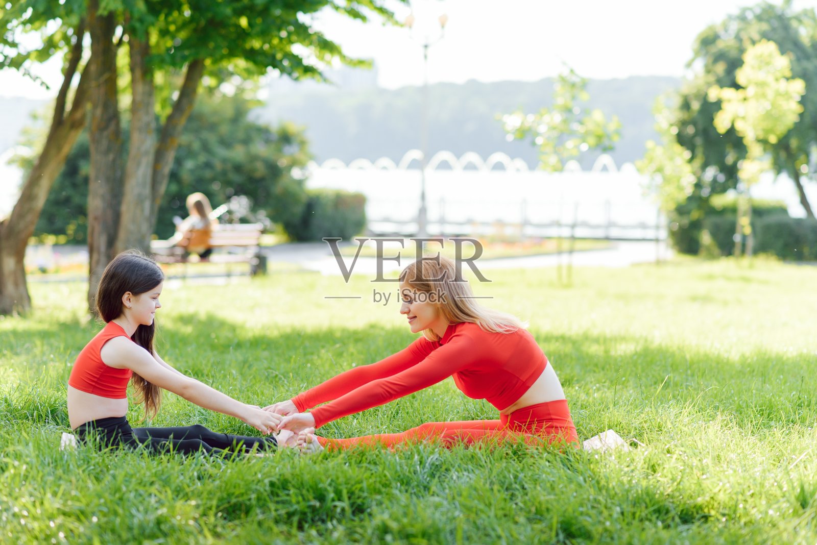 白天，母亲和女儿在公园的草地上做瑜伽练习照片摄影图片