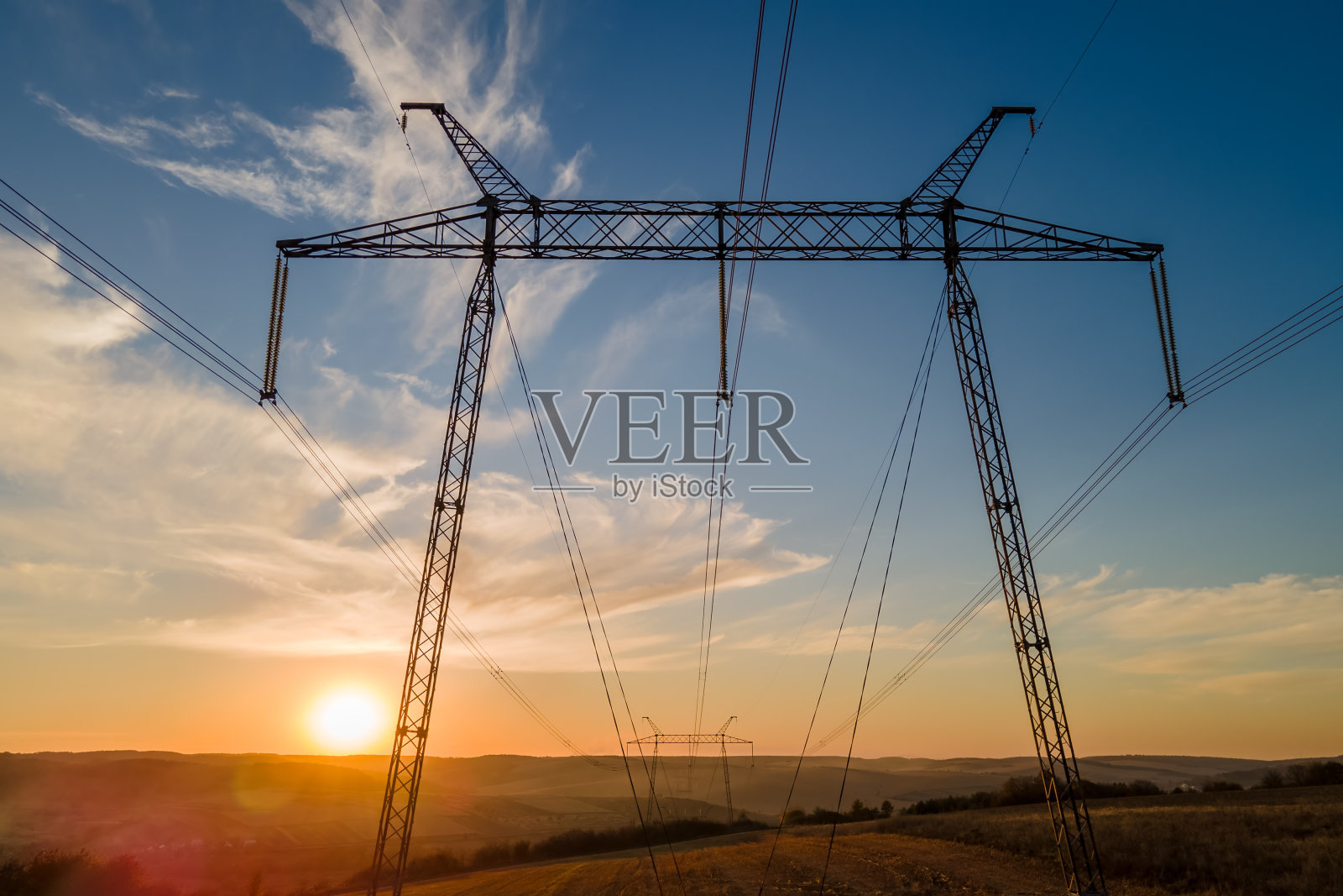 深色轮廓的高压塔与电力线路在日出。传输电能的概念照片摄影图片