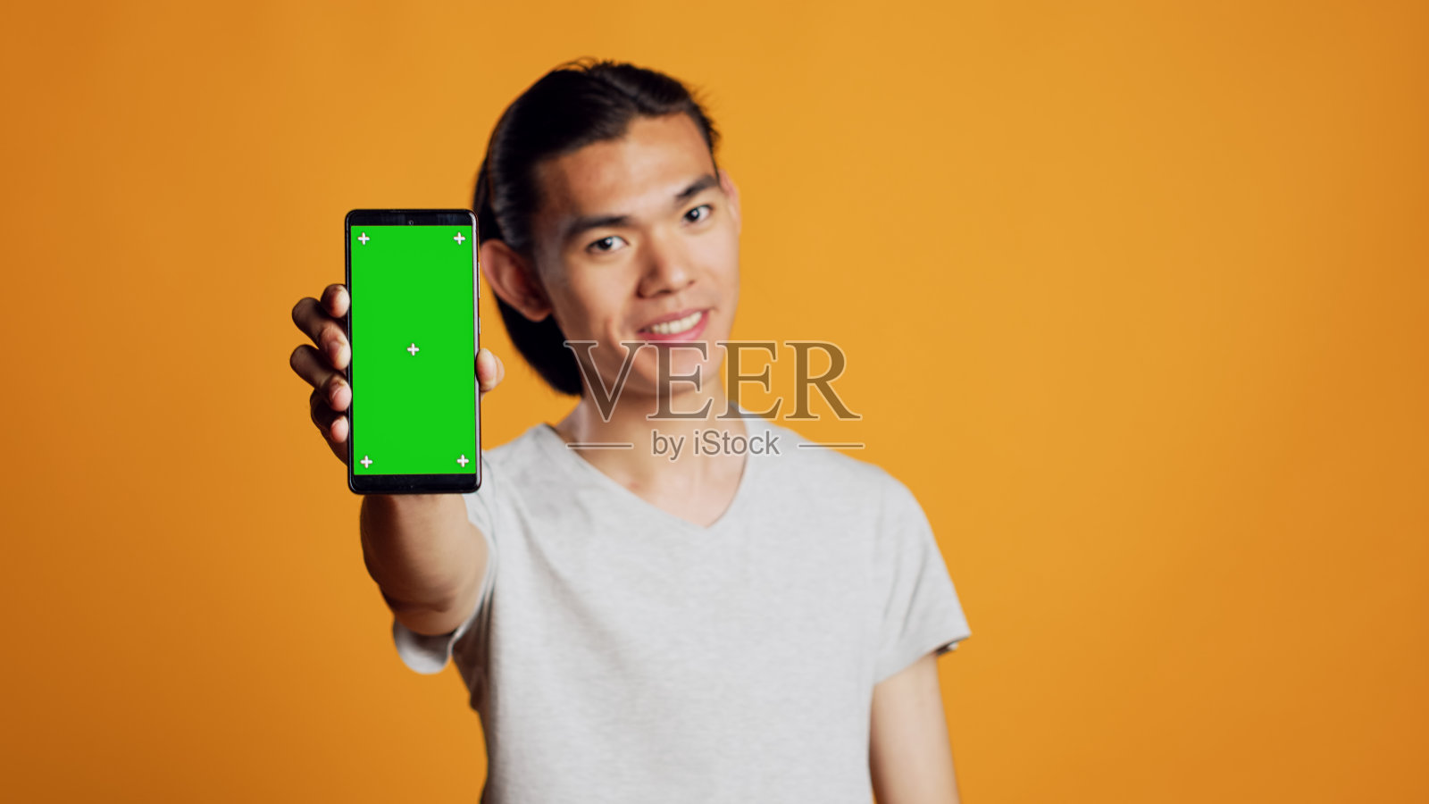 快乐的年轻人展示绿色屏幕的手机照片摄影图片