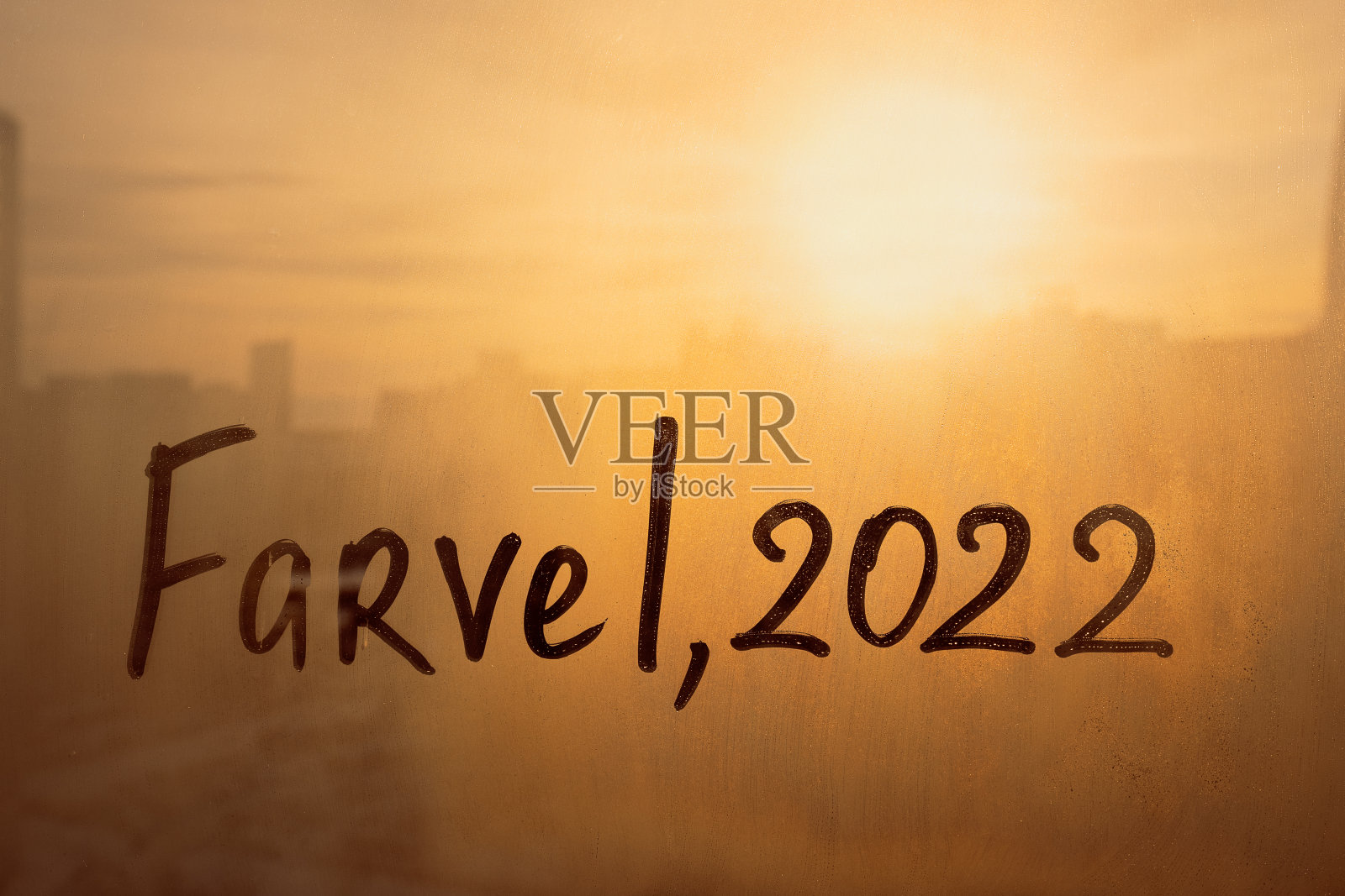 丹麦语中的Farvel是英语中的bye，数字是2022，用手指的水涂在雨溅到日落窗户上的雾玻璃上照片摄影图片