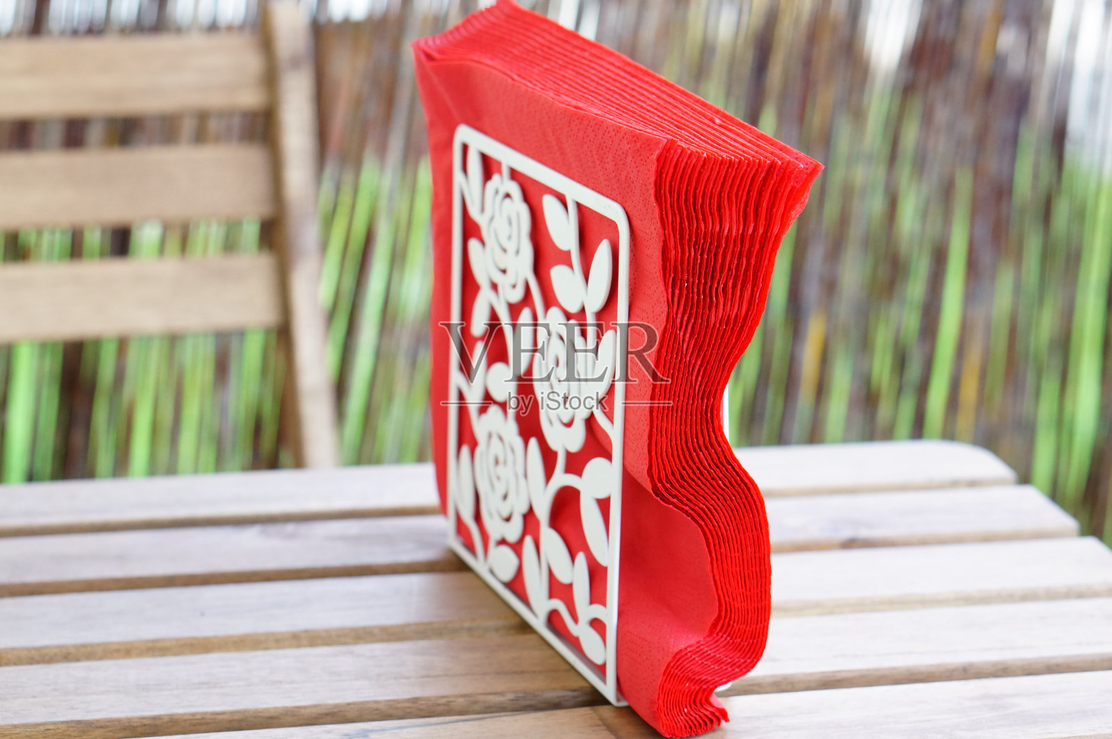 在户外的木桌上，红色的餐巾放在白色的装饰餐巾架上照片摄影图片