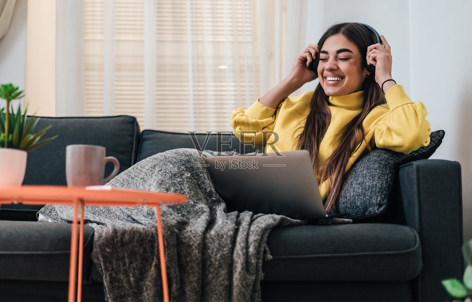 快乐的年轻白人女性，戴上耳机，使用笔记本电脑。照片摄影图片