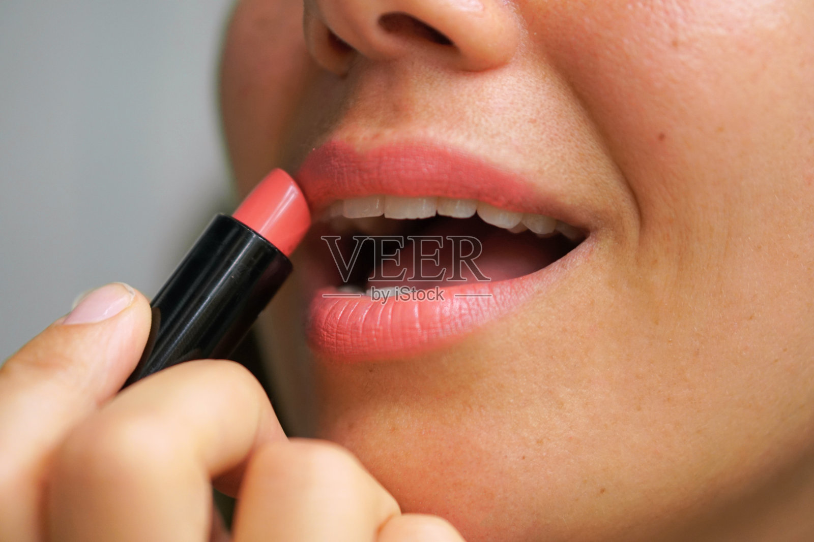 一个女孩涂口红的特写。照片摄影图片
