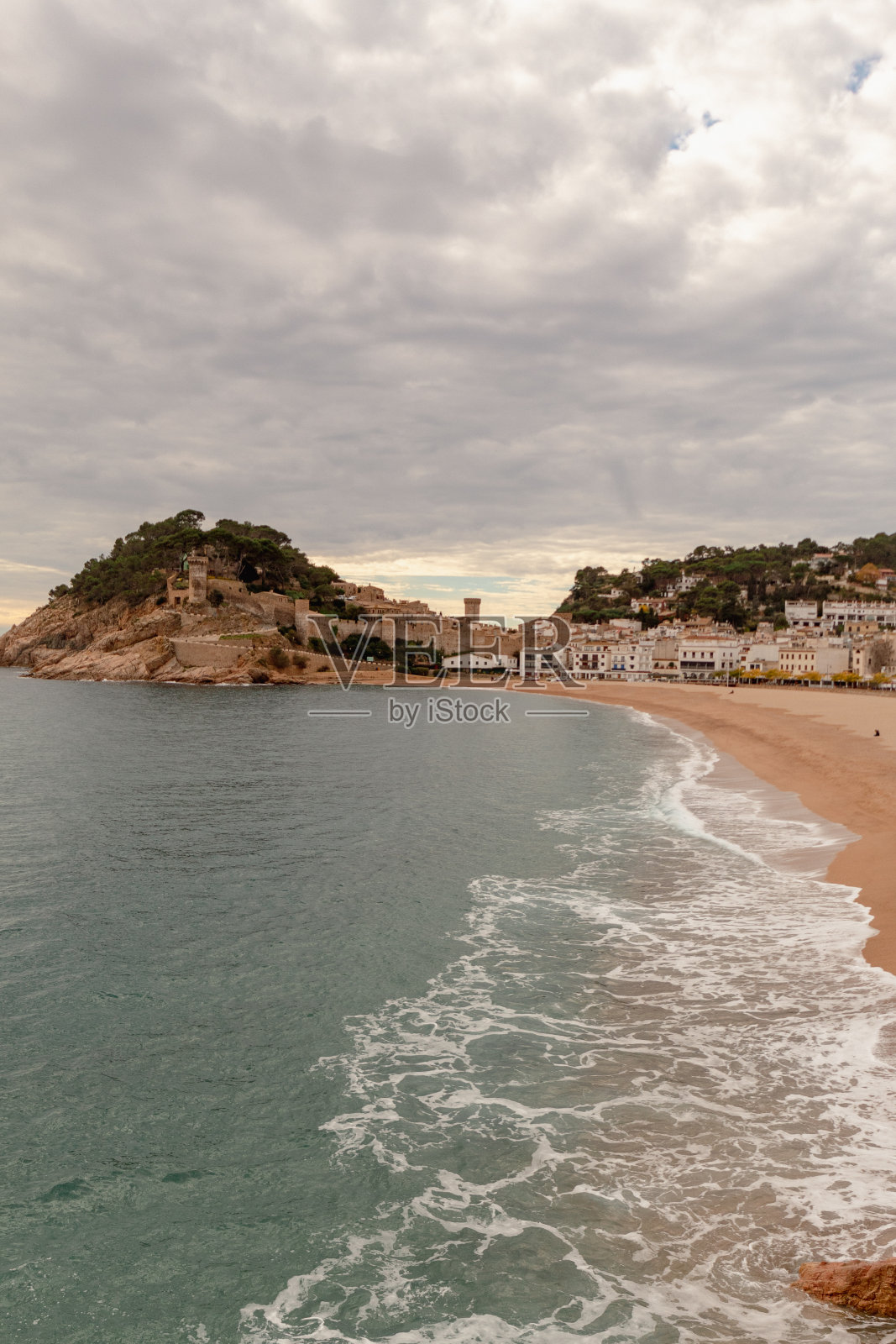 赫罗纳的tosa de Mar海滩全景，背景是山上的城堡，在特殊的天空下有云。照片摄影图片