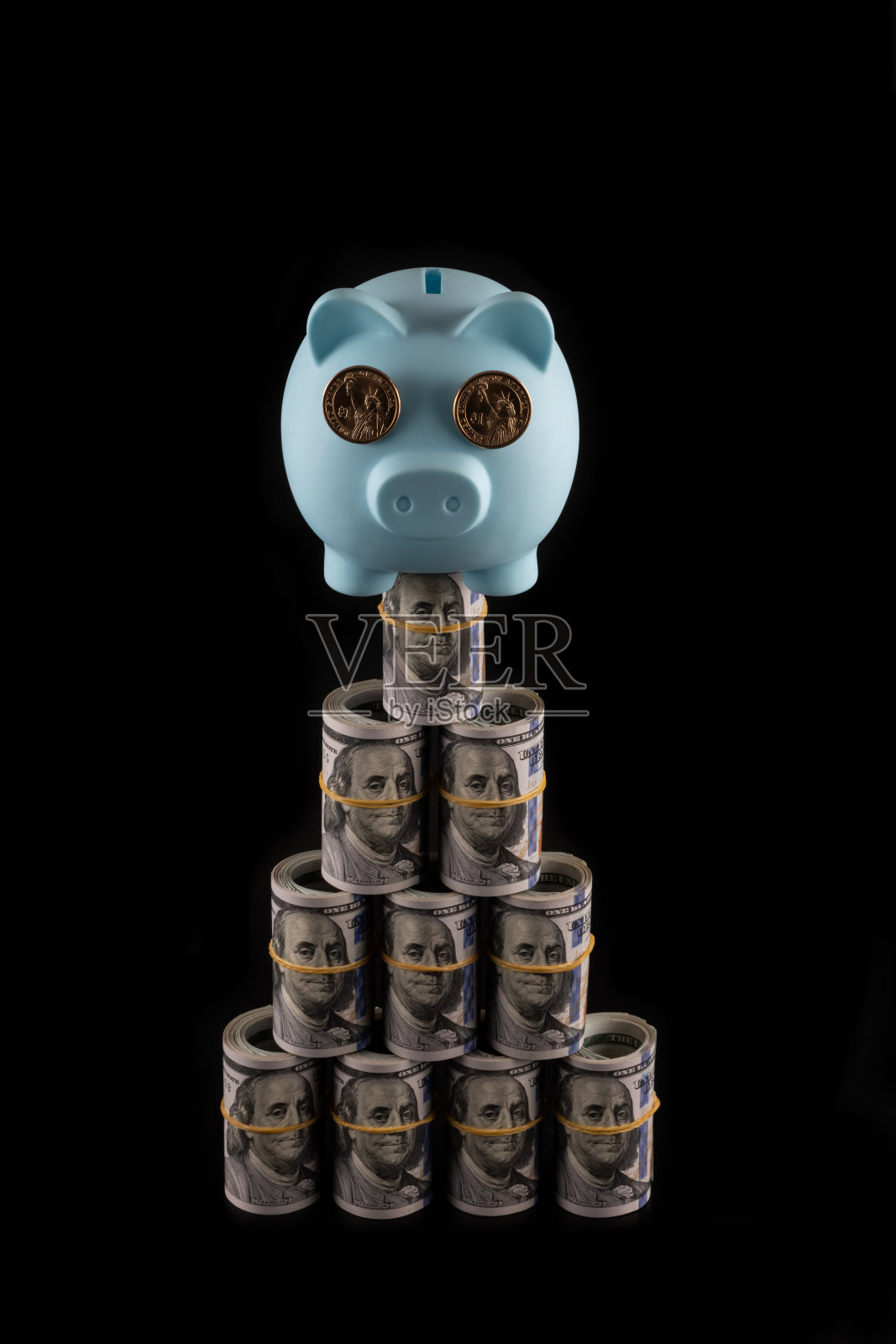 一个蓝色的存钱罐，里面有1美元硬币和一个折叠的100美元纸币的金字塔照片摄影图片