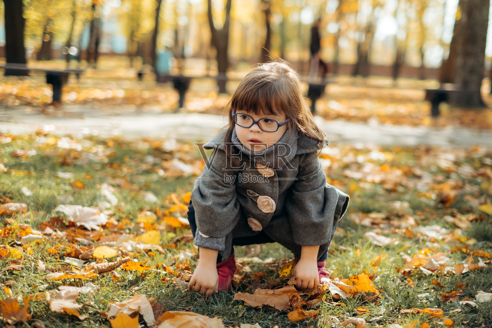 快乐可爱的女孩穿着时髦的外套戴着时髦的眼镜走着笑着，孩子在温暖的秋日公园里享受时光，童年快乐照片摄影图片