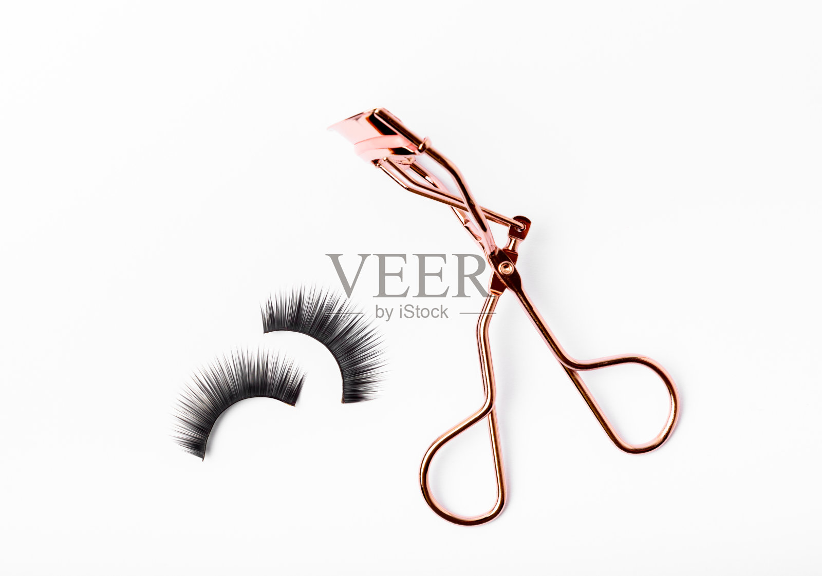 睫毛夹和假睫毛隔离在白色背景上。美丽的概念。化妆。发短信的地方。副本的空间。照片摄影图片