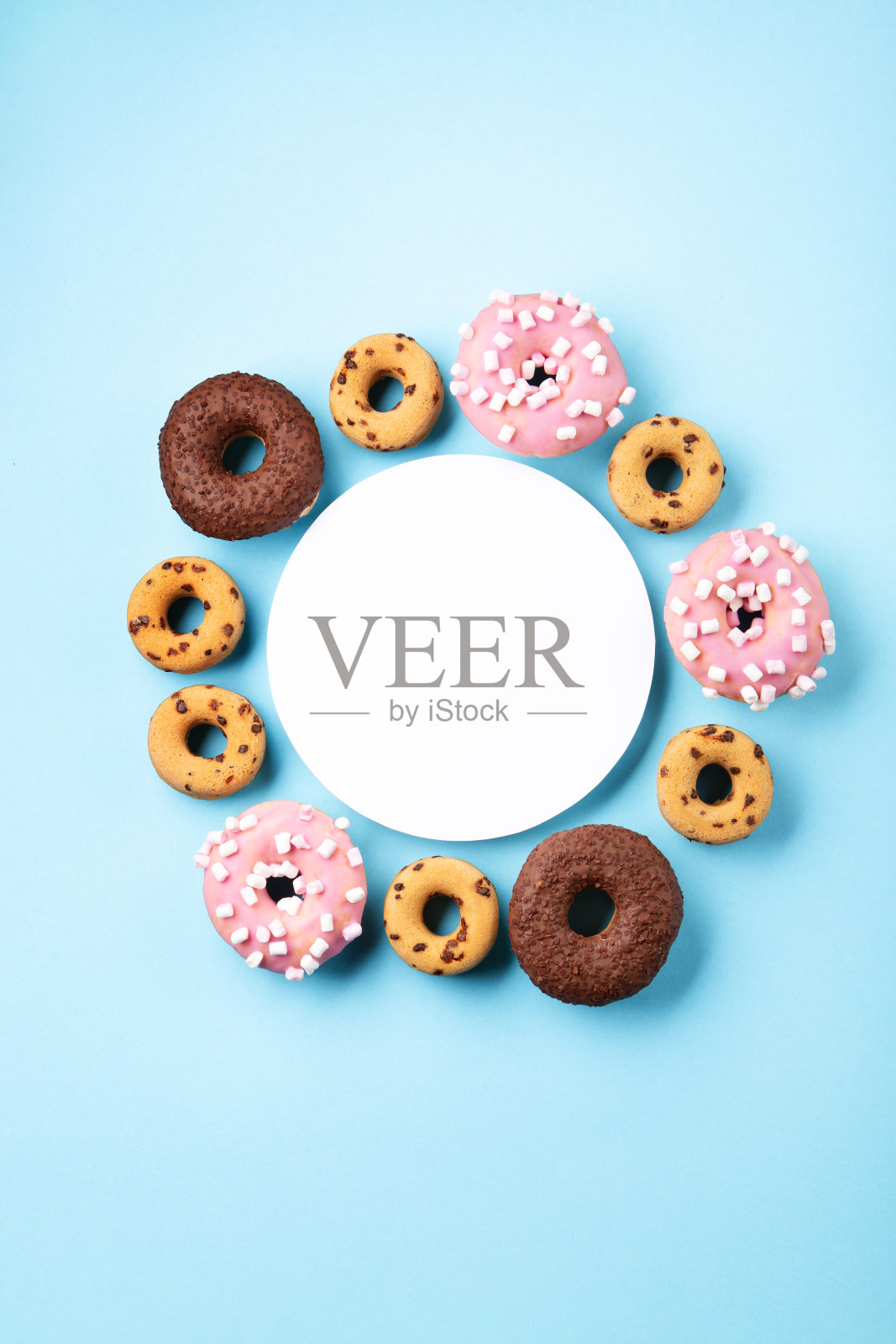 巧克力甜甜圈，粉色棉花糖和糖洒在蓝色的背景照片摄影图片