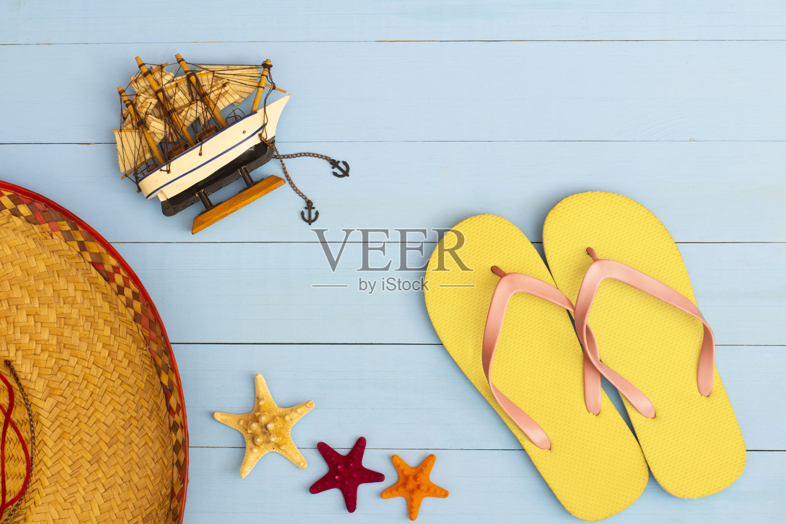 酷的观点涂浅蓝色木桌人字拖，帆船，帽子，和海星照片摄影图片