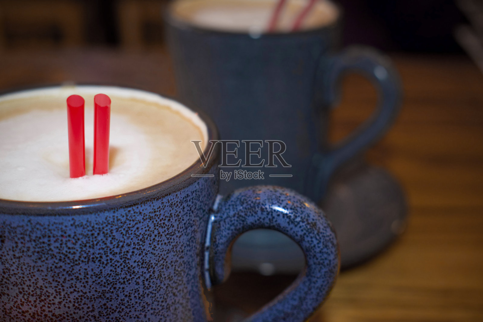 一杯拿铁咖啡的特写镜头被另一杯咖啡的蓝色陶瓷镜面所映照照片摄影图片