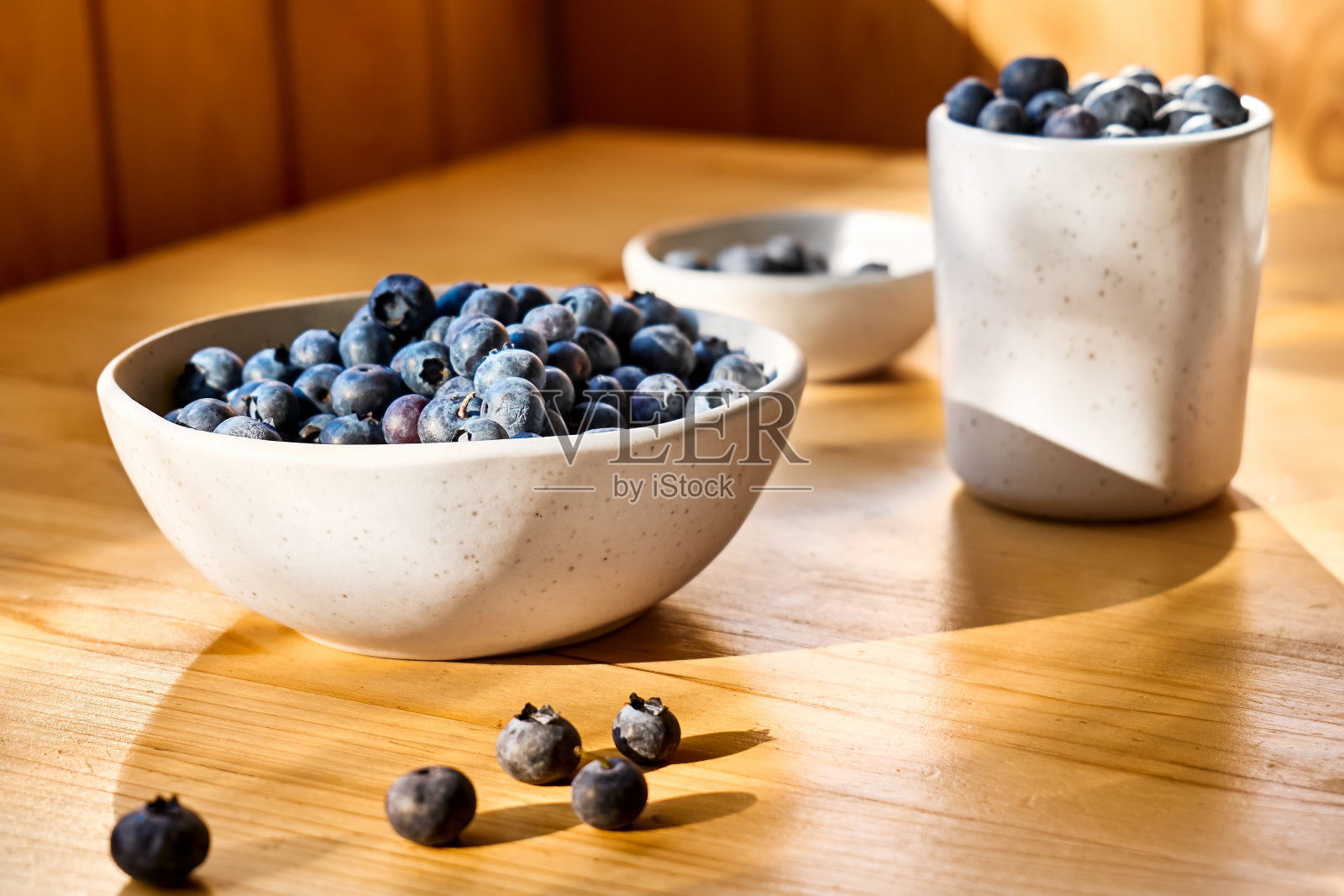 新鲜的有机蓝莓。多汁成熟的越桔装在白色碗里，放在木桌上。抗氧化和健康饮食的概念。照片摄影图片