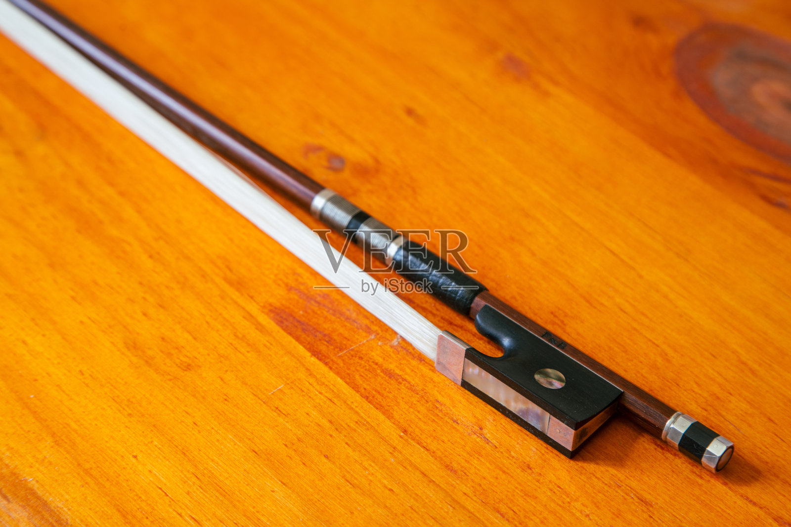 在制琴师的作坊里，一张明亮的桌子上放着需要修理的破损的小提琴弓照片摄影图片