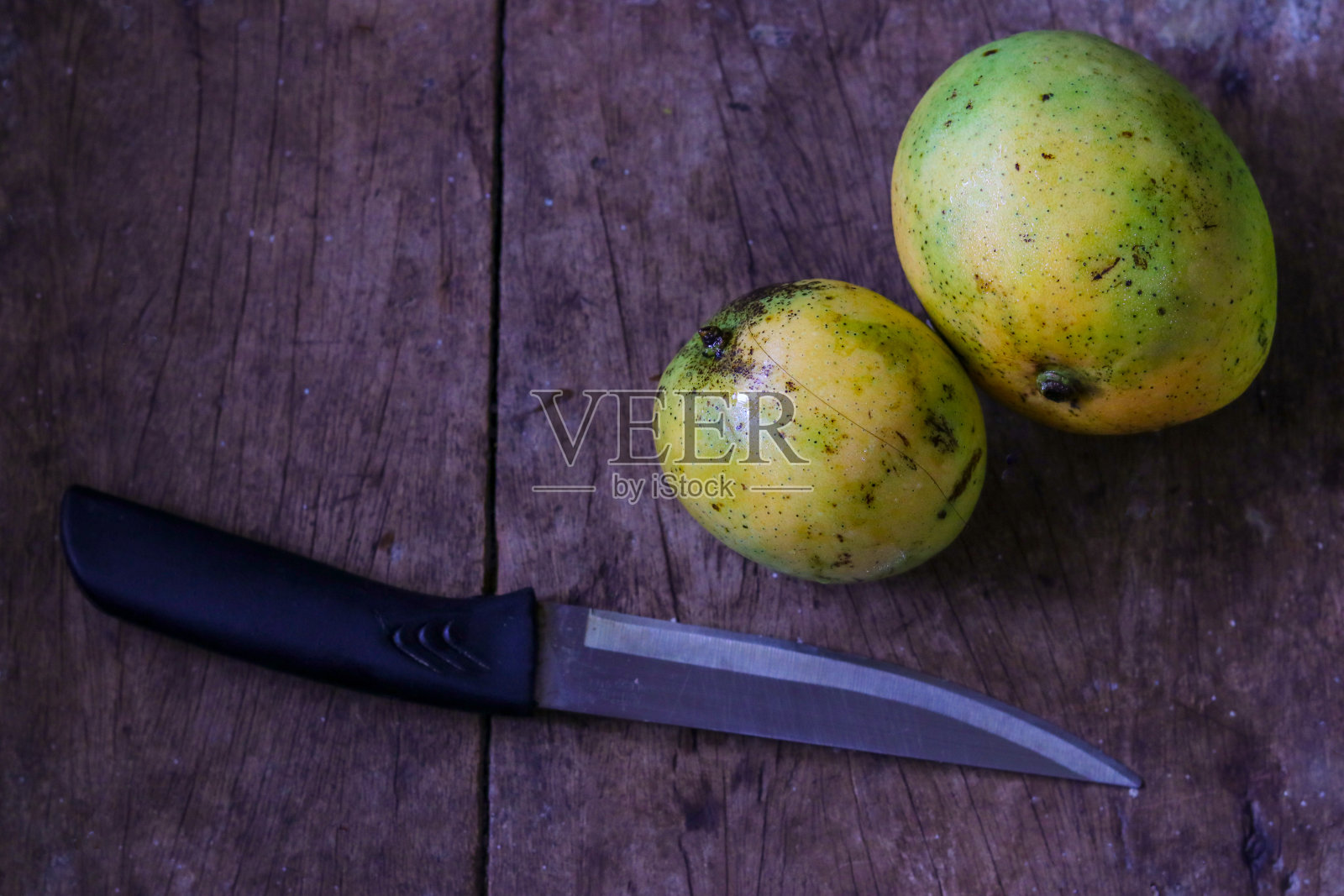 俯视图新鲜的黄色芒果孤立在木桌上与锋利的菜刀照片摄影图片