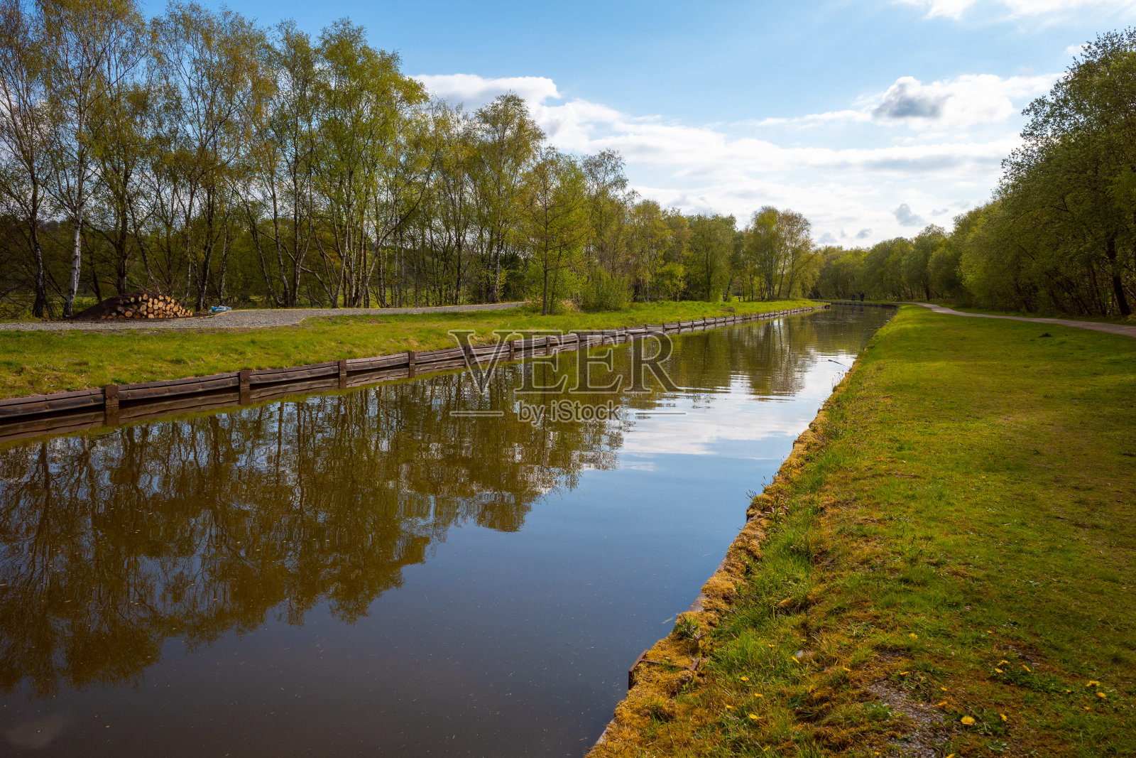 在英国大曼彻斯特的布斯敦，运河两旁有道路和树木照片摄影图片