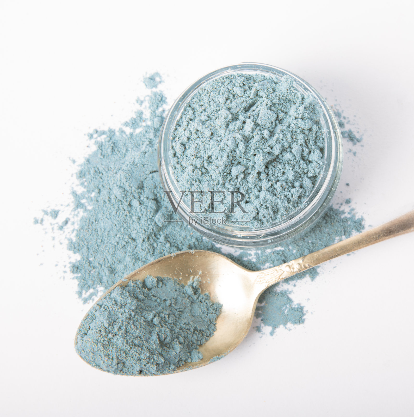蓝色螺旋藻粉在玻璃罐和勺子分离在白色背景。天然素食超级食物。食物补充。藻青蛋白提取。照片摄影图片