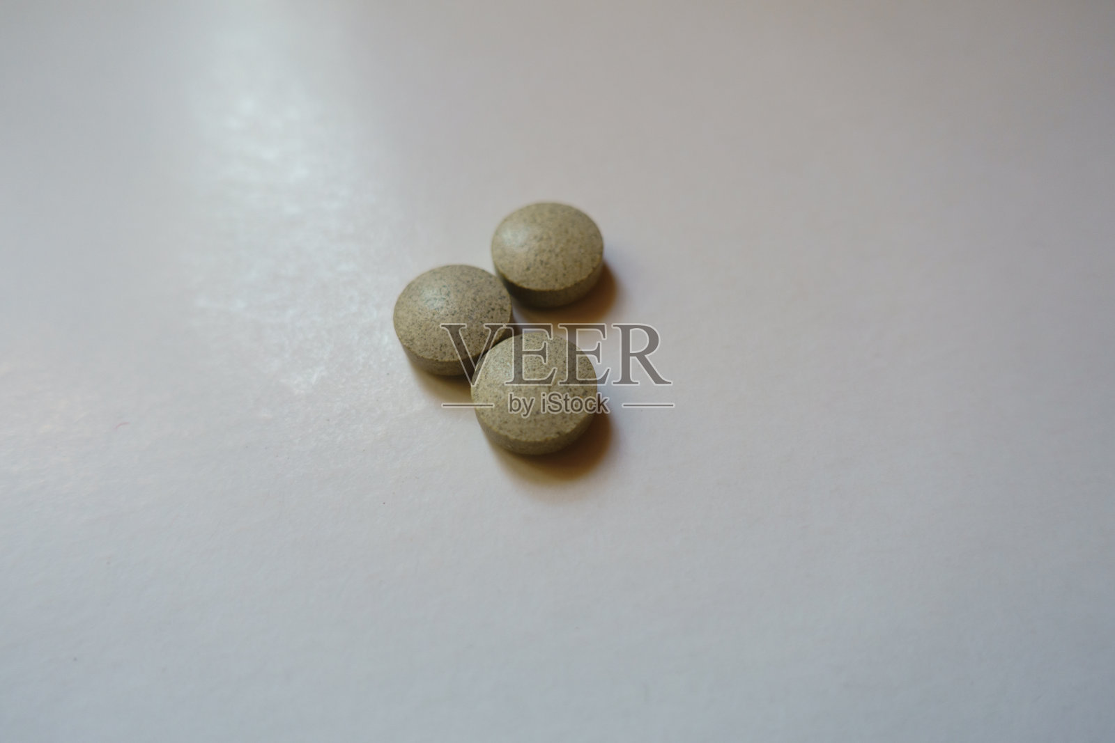 特写三个米色圆形药丸的铁甘氨酸膳食补充剂照片摄影图片