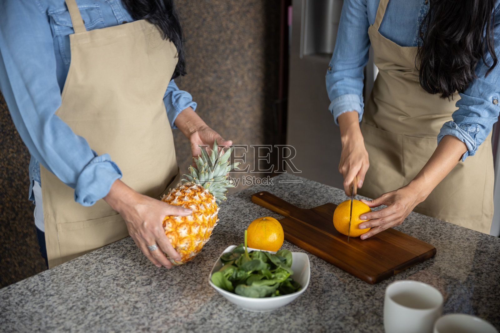 一个女人的手在厨房的砧板上切橘子和菠萝的特写照片摄影图片