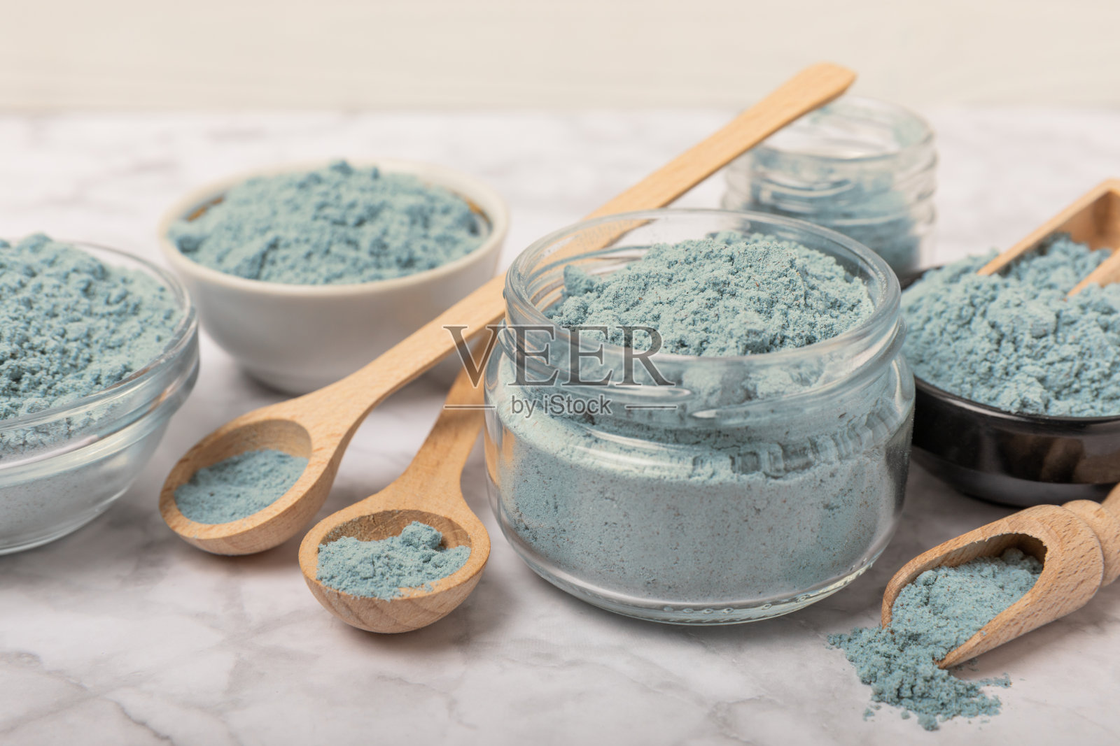 蓝色的螺旋藻粉装在玻璃罐里，木勺放在白色大理石桌上。天然素食超级食物。食物补充。藻青蛋白提取。健康的食物。发短信的地方。副本的空间。照片摄影图片