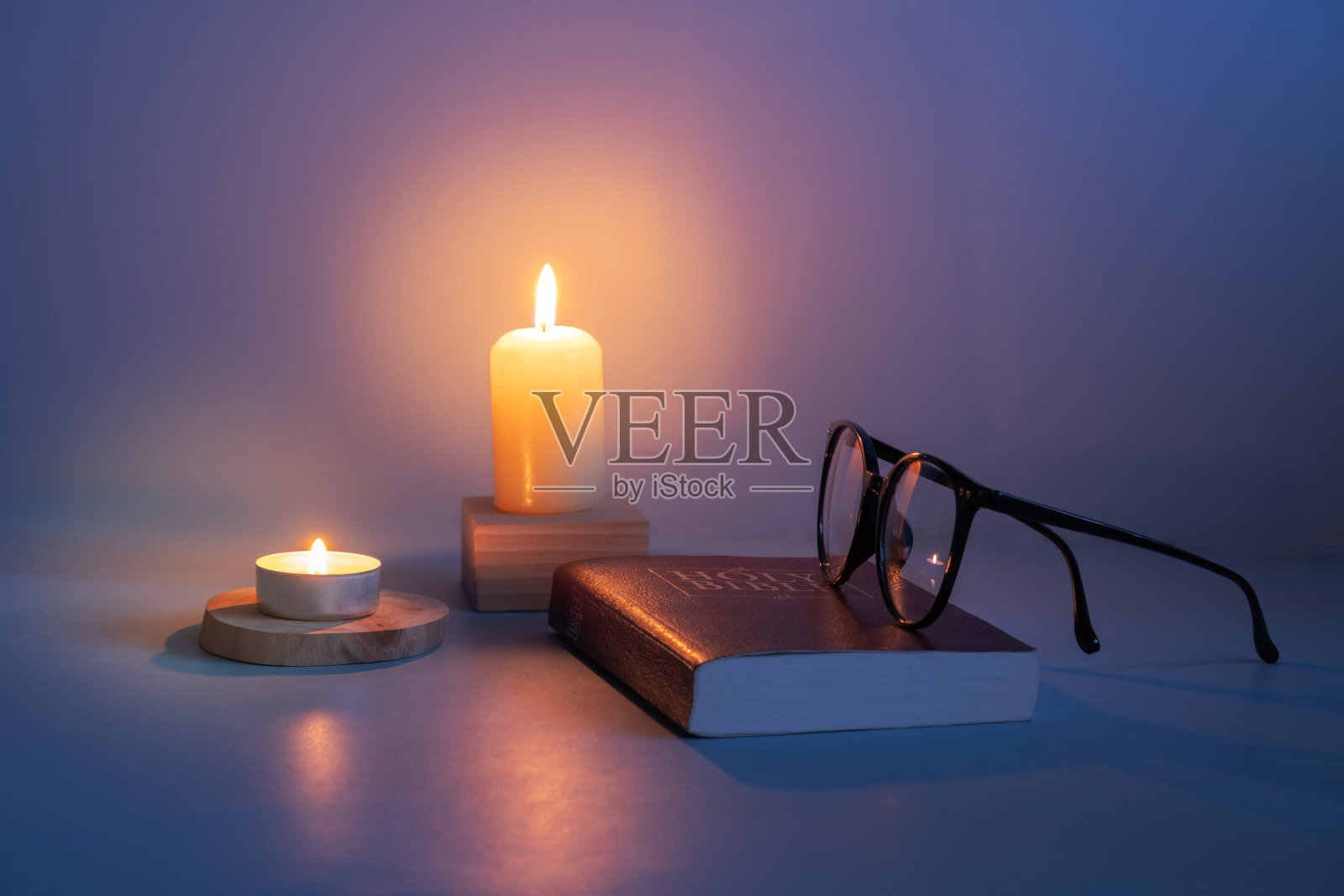 眼镜和圣经与蜡烛火焰在黑暗中。照片摄影图片