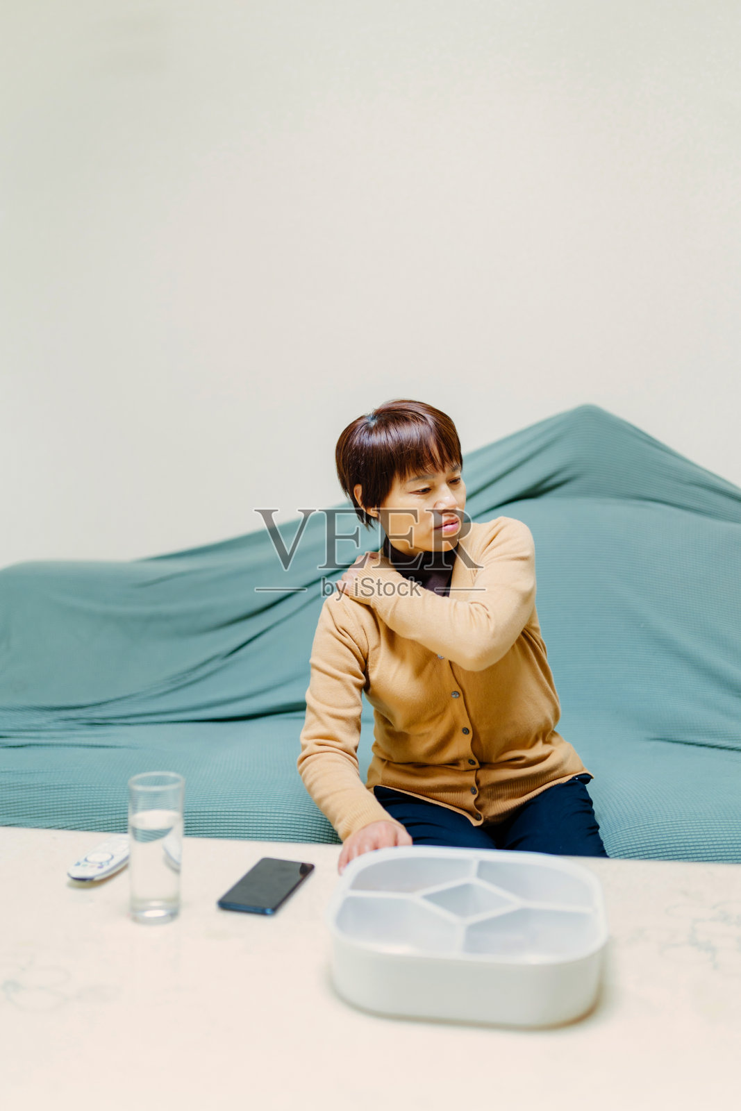 一位中年妇女在沙发上感到身体疼痛——身体健康、生活方式、医疗健康照片摄影图片