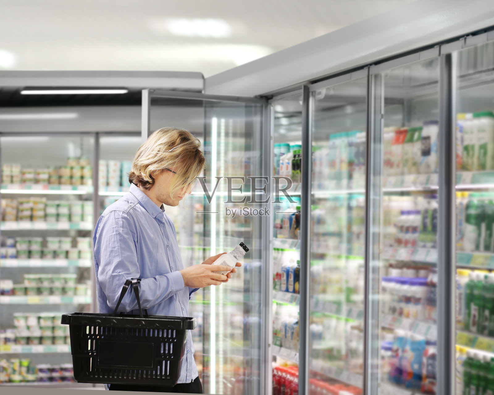 男人从超市冰柜选择冷冻食品并阅读产品信息照片摄影图片