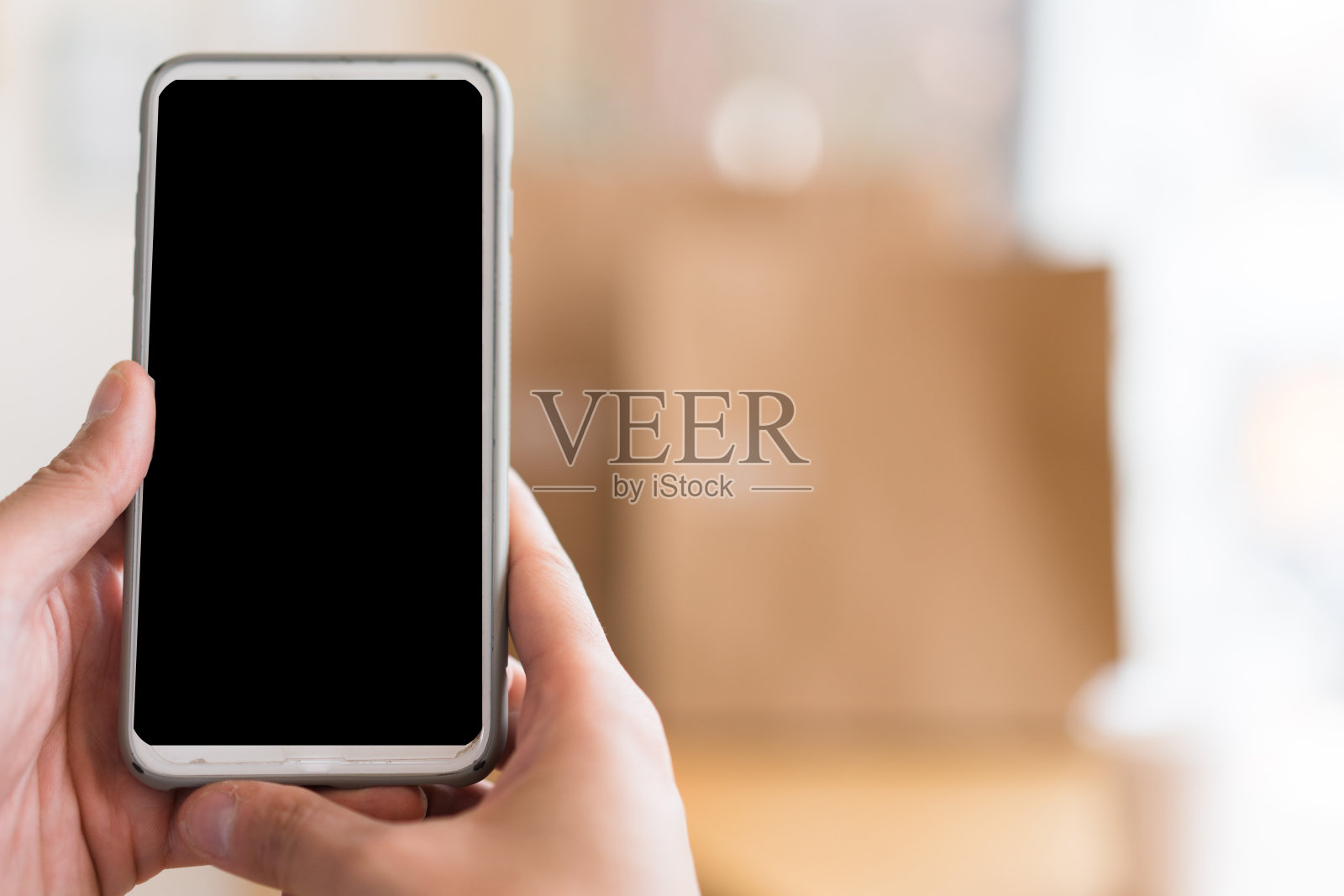 近距离观察使用中的技术。在家庭办公室工作的男子手持智能手机。在通信中使用技术的概念。照片摄影图片