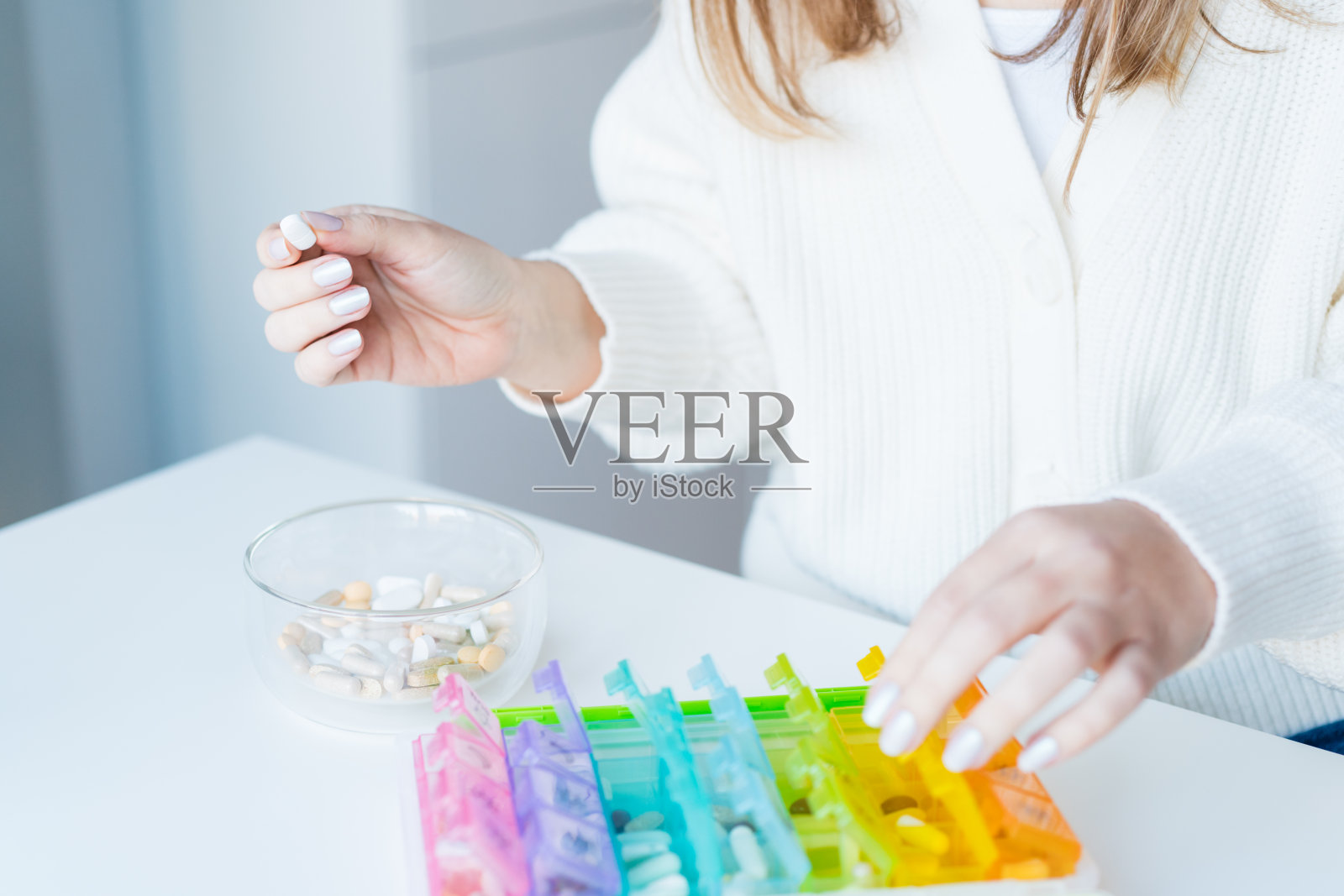 女人的手在整理药片。关闭药箱与每日剂量的药物。抗氧化饮食维生素补充剂保健美容，生物黑客概念。照片摄影图片