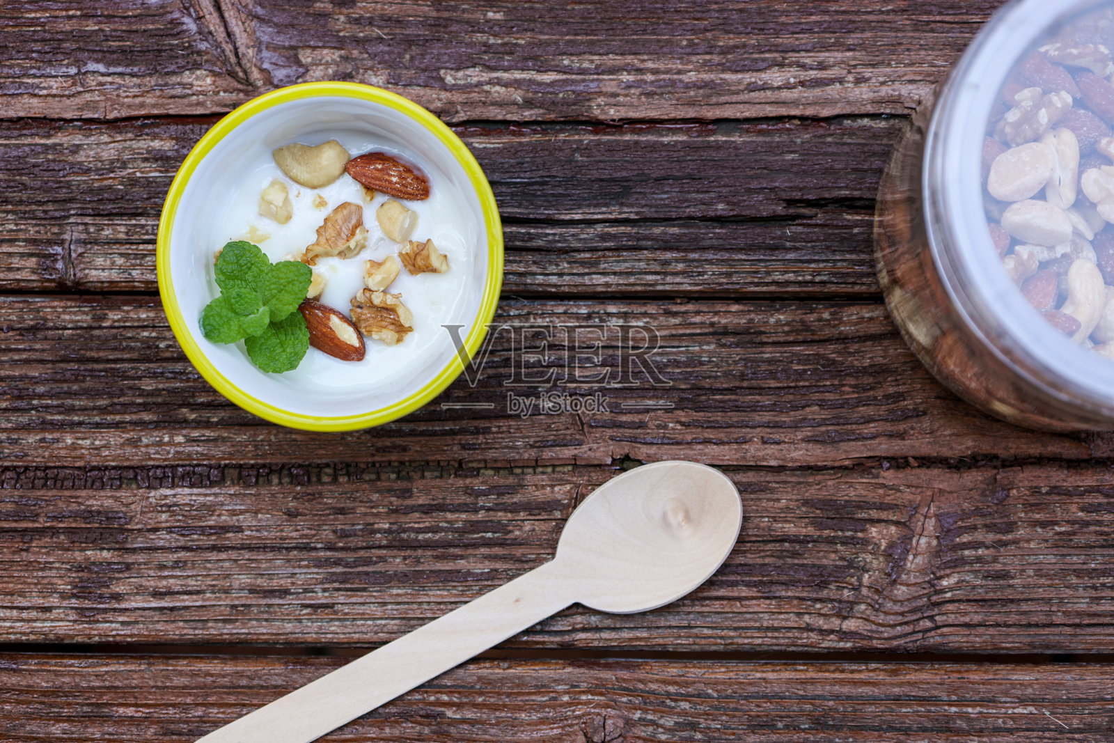 木桌上放着坚果酸奶。照片摄影图片