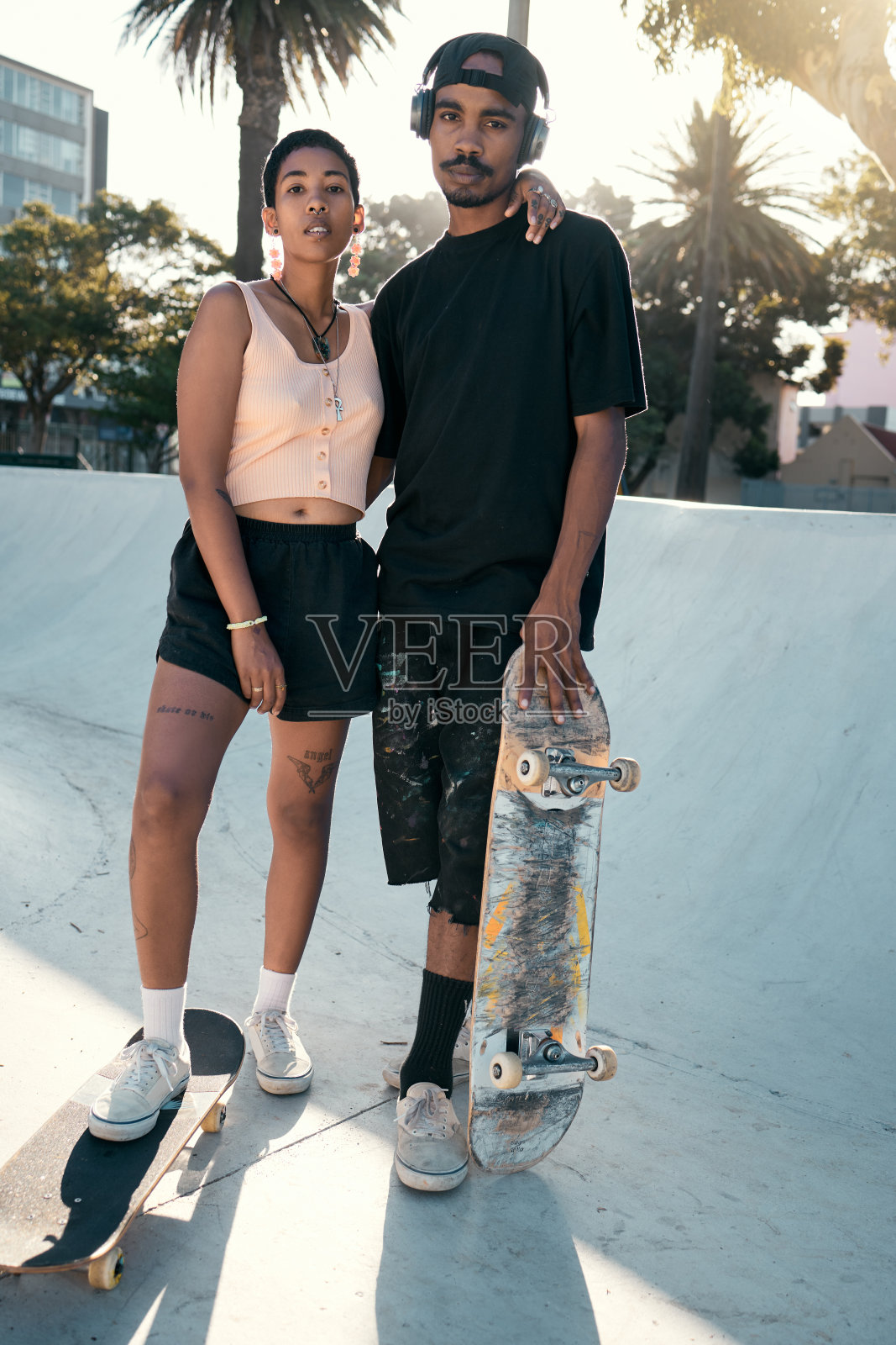 在户外的滑板公园进行训练，锻炼和娱乐，玩滑板，滑冰情侣和城市运动。时髦的男人和女人出去滑冰锻炼，滑板和休闲的城市生活方式照片摄影图片