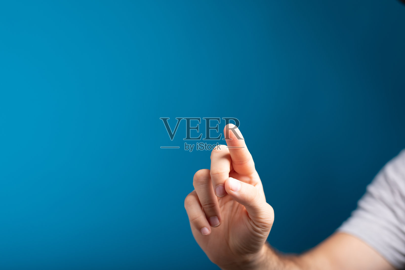 一个男人手指触摸屏幕的特写镜头，背景是蓝色的照片摄影图片