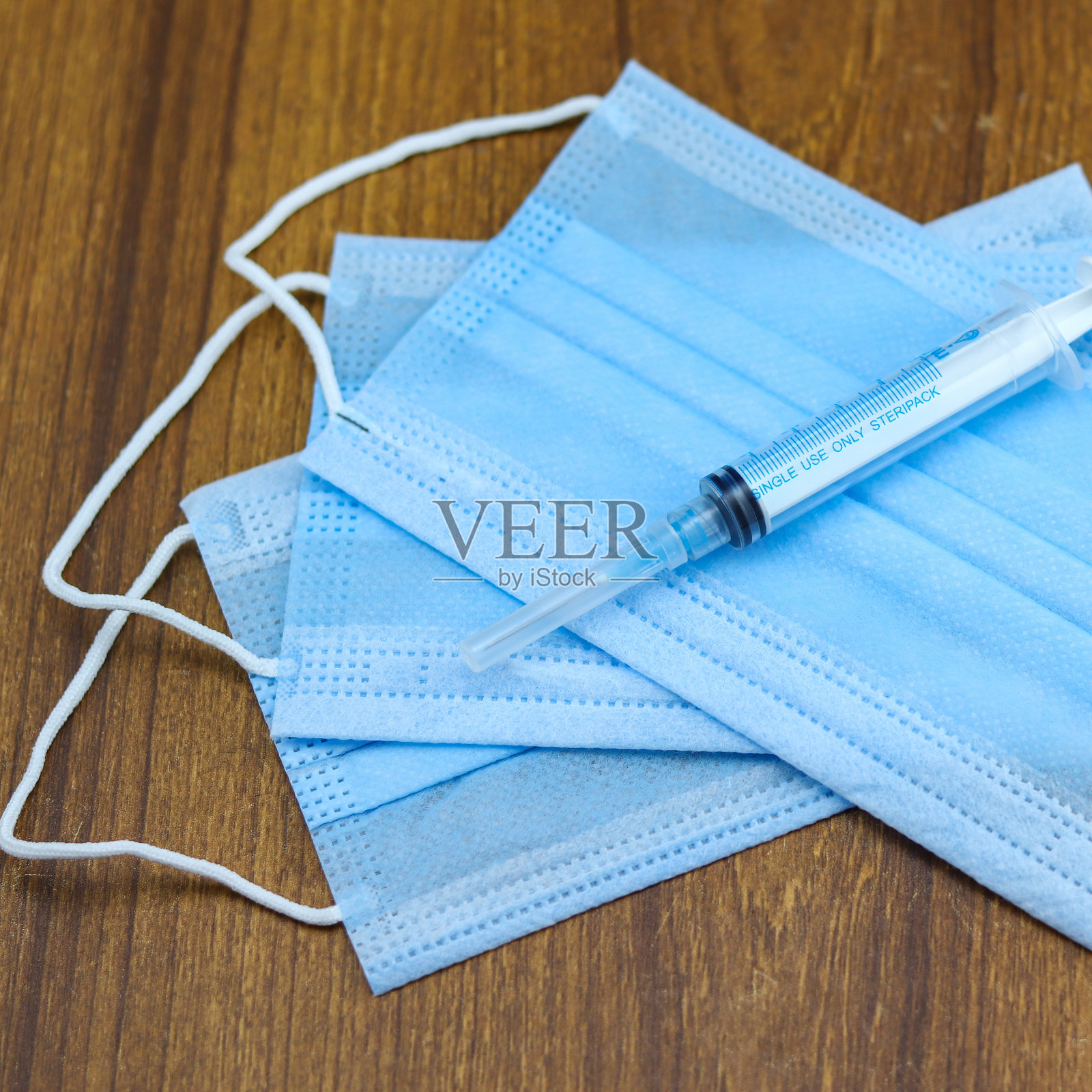 木制背景口罩上的注射器- Covid-19大流行照片摄影图片