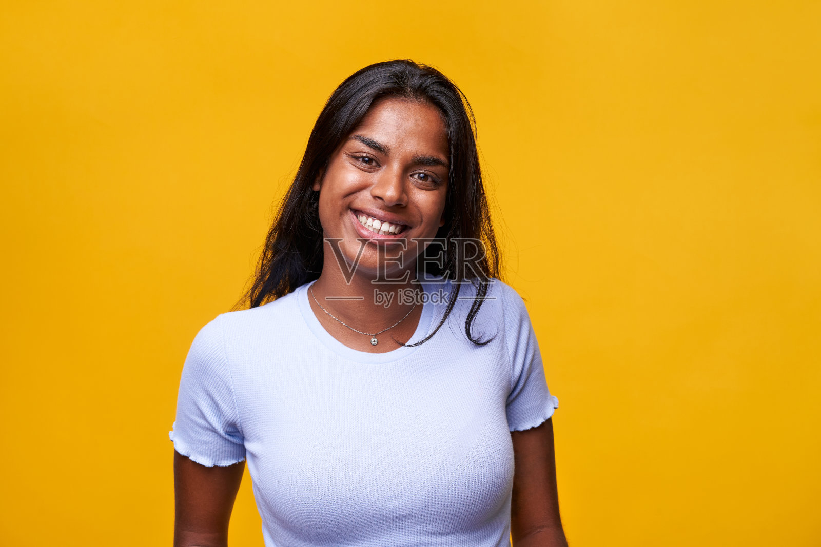 年轻的印度妇女看着相机和微笑的肖像在彩色工作室拍摄。照片摄影图片