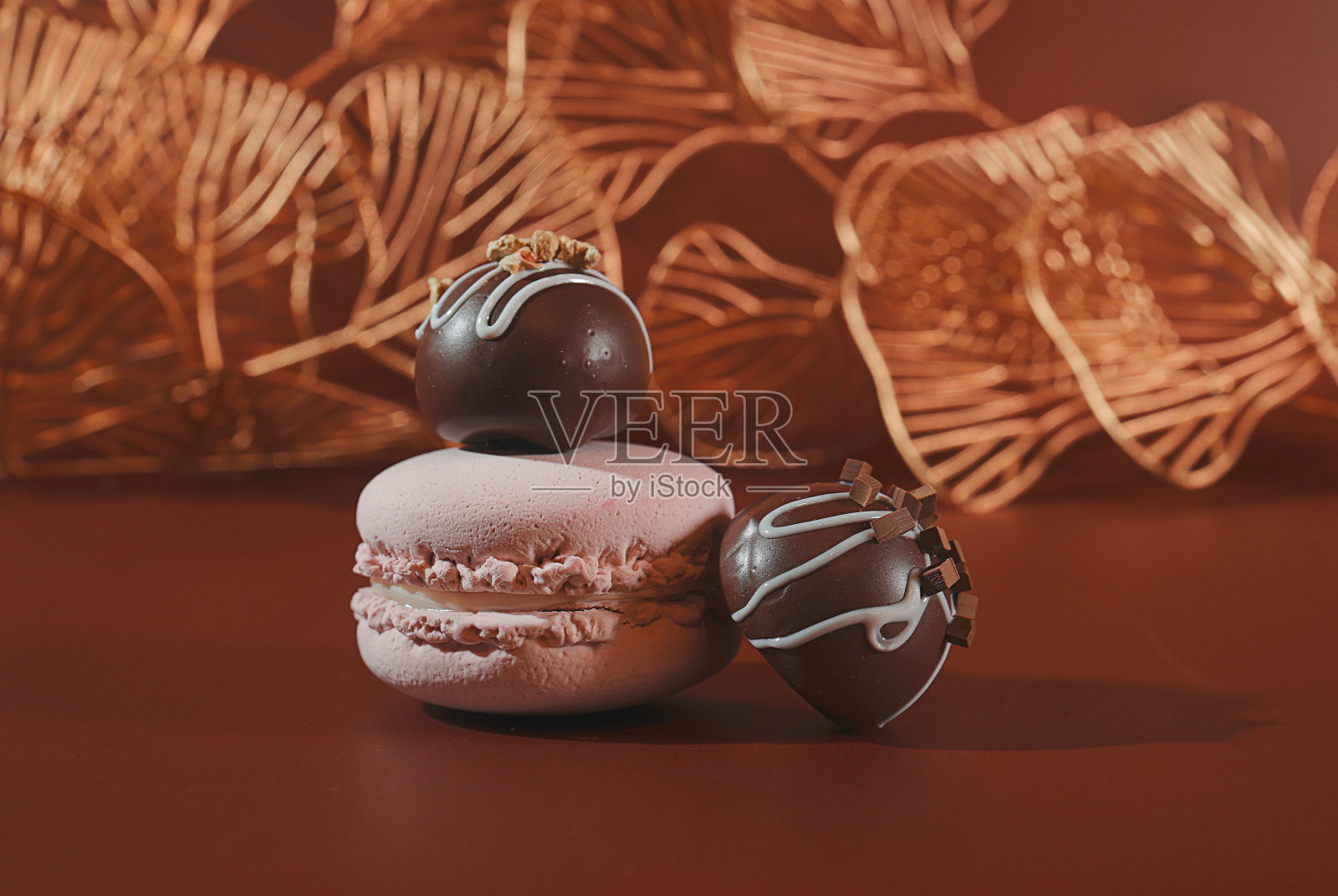 甜品:巧克力糖果和粉色法式马卡龙饼干，背景是金色的银杏叶照片摄影图片