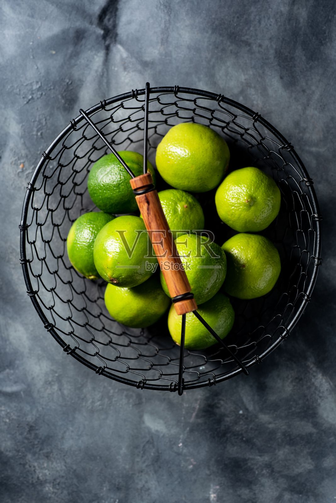 近距离的绿色柠檬在一个篮子上的木制表面照片摄影图片