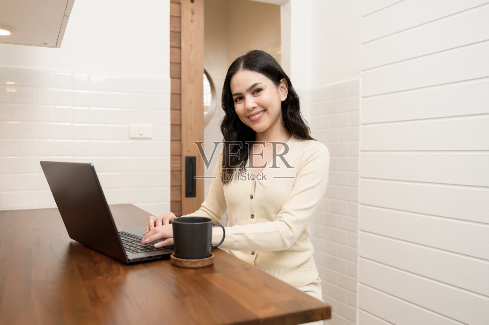 一个亚洲年轻女性使用笔记本电脑在家在线工作，生活方式和远程办公的概念照片摄影图片