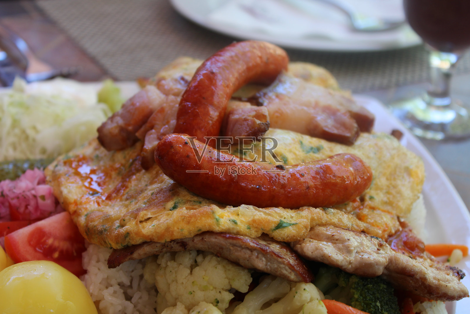 一盘米饭配煎蛋卷、香肠、蔬菜沙拉和烤肉照片摄影图片