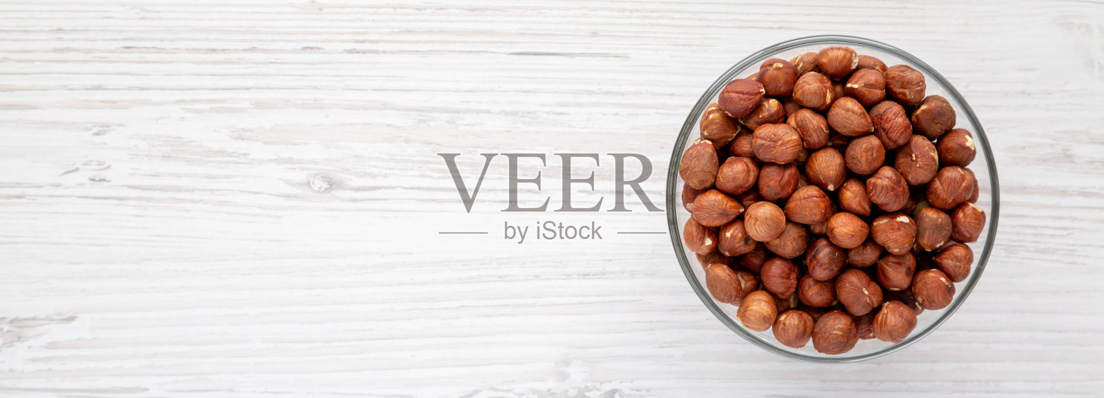 在一个白色木制背景上的碗里的未壳榛子，俯视图。平躺，头顶，从上面。照片摄影图片