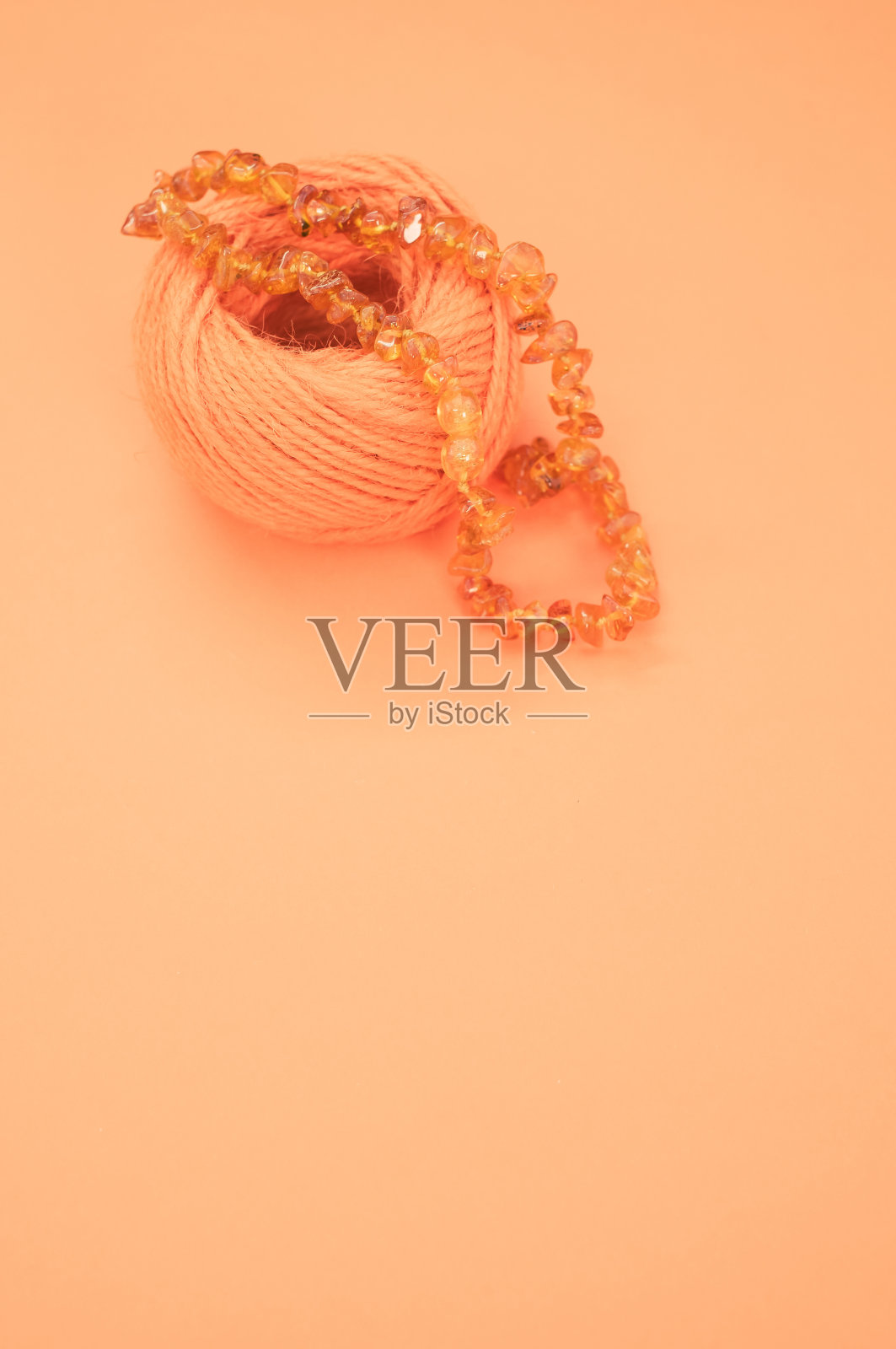 一个琥珀珠子项链和棉纱在橙色表面的特写镜头照片摄影图片