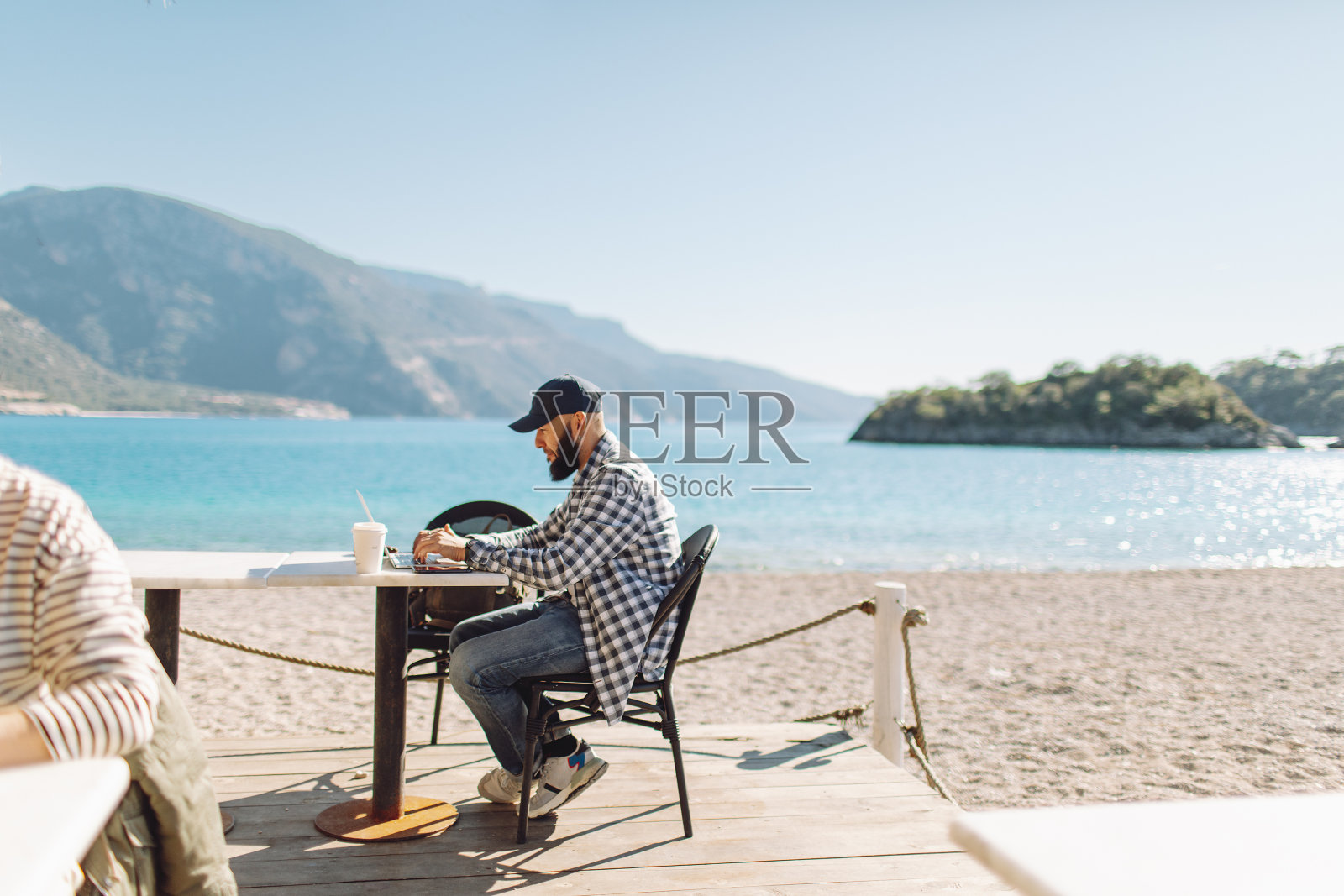 年轻的成年男子在海滩咖啡馆使用笔记本电脑工作照片摄影图片