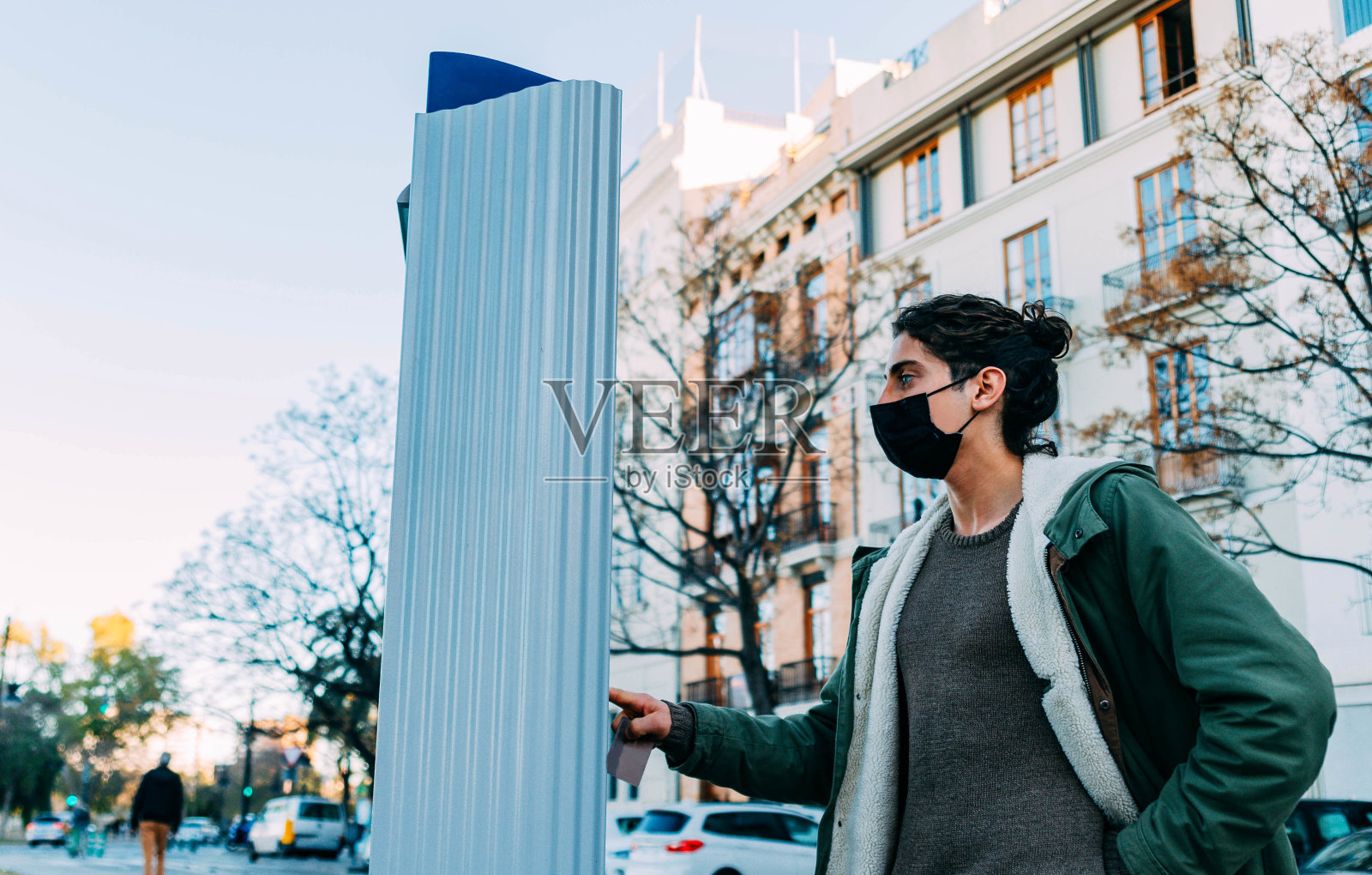 年轻的白人男子戴着面具，拿着城市自行车租赁站的票证照片摄影图片