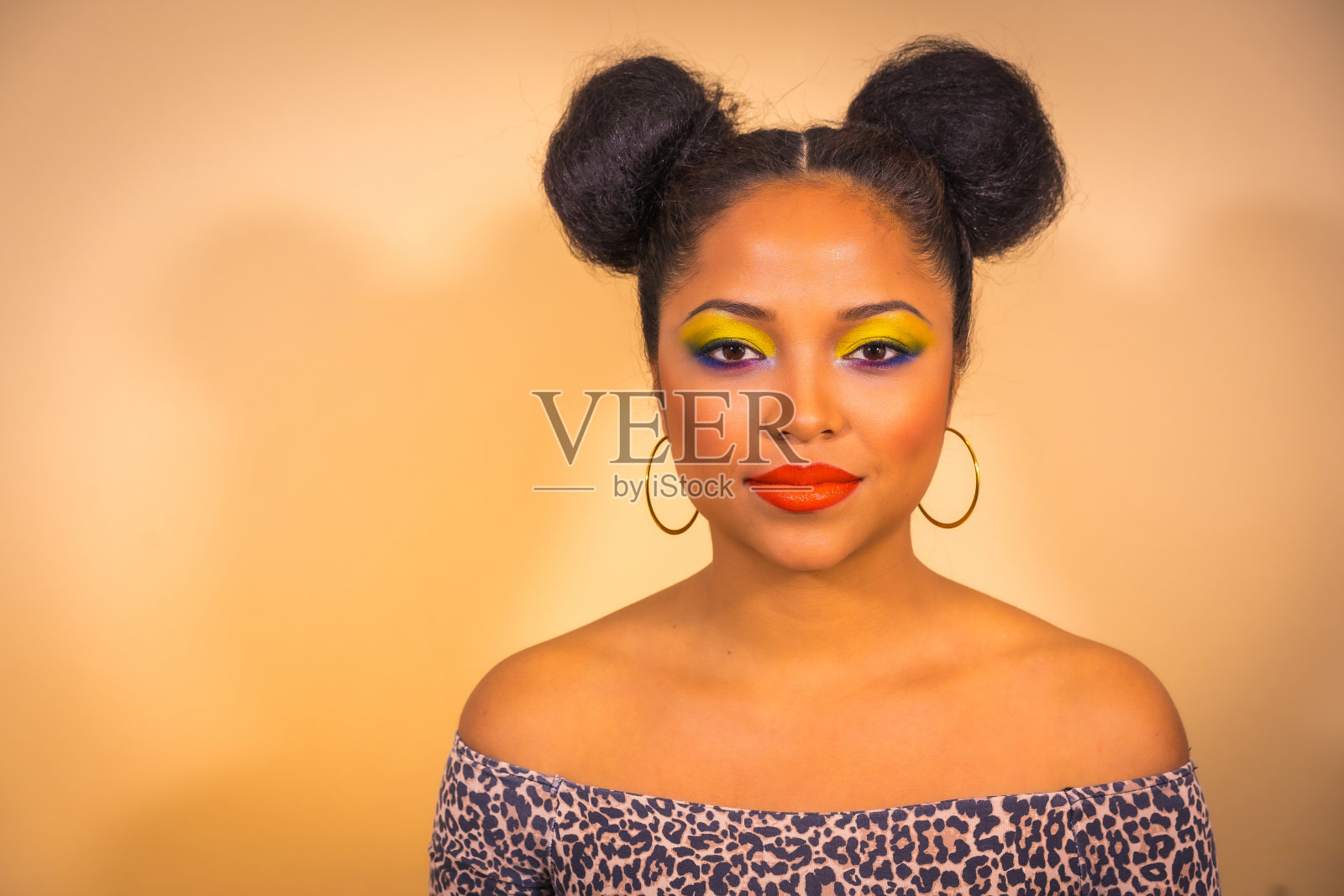 一个性感性感的女人与明亮的妆容和两侧发髻在工作室摆姿势照片摄影图片